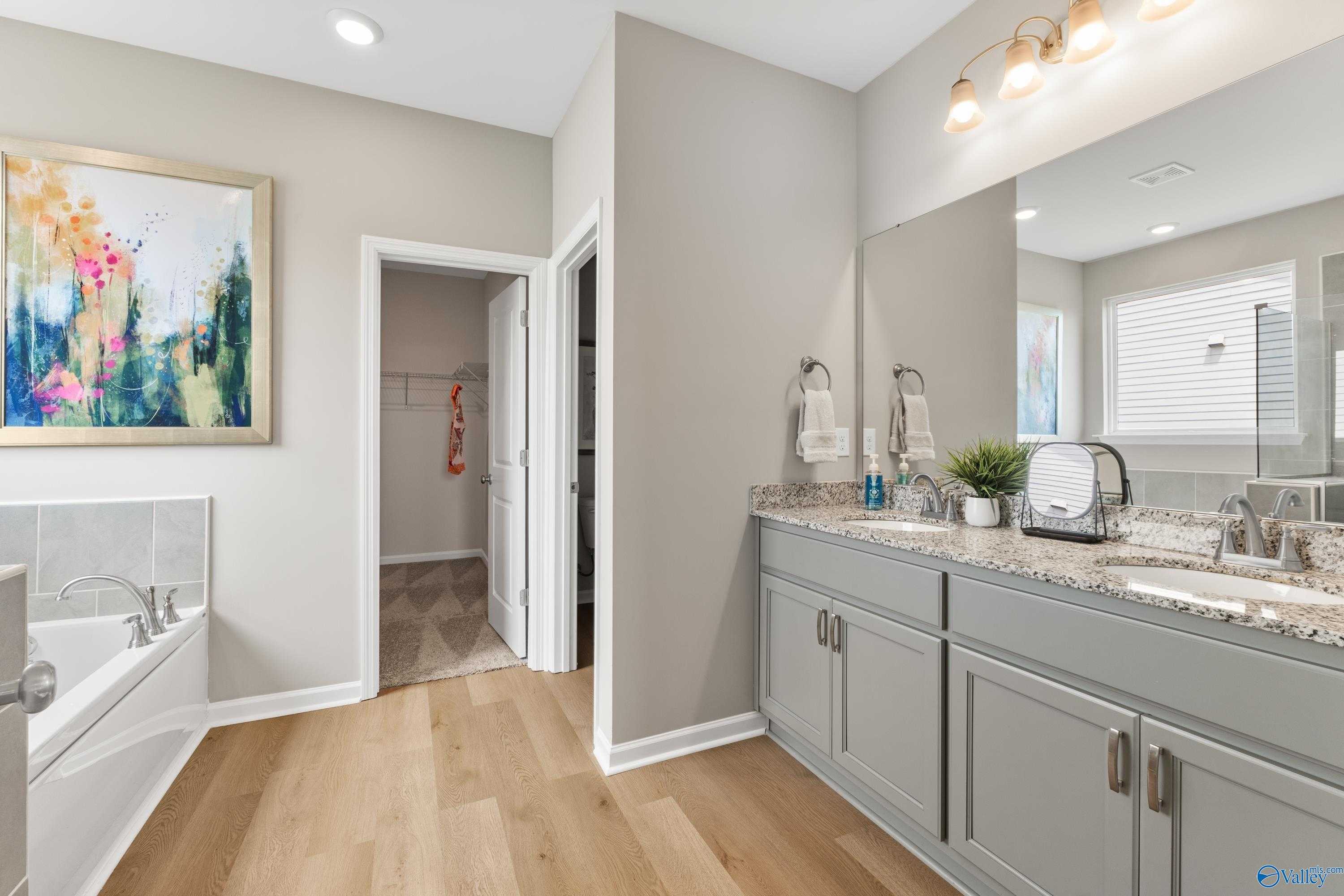 Elegant master bathroom featuring double vanity, soaking tub, and walk-in closet in Davidson Homes The Sanctuary, Athens AL