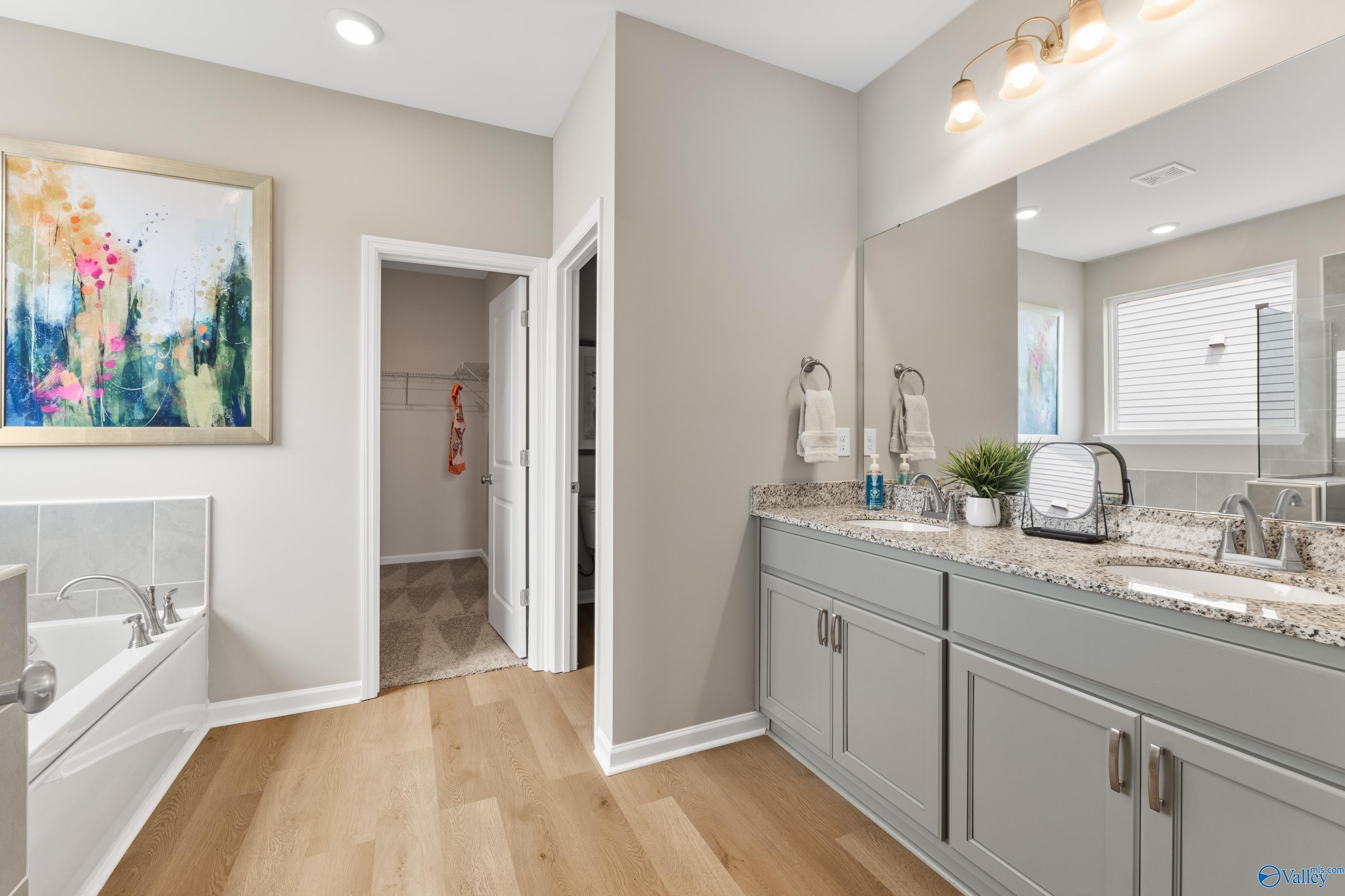 Elegant master bathroom featuring double vanity, soaking tub, and walk-in closet in Davidson Homes The Sanctuary, Athens AL