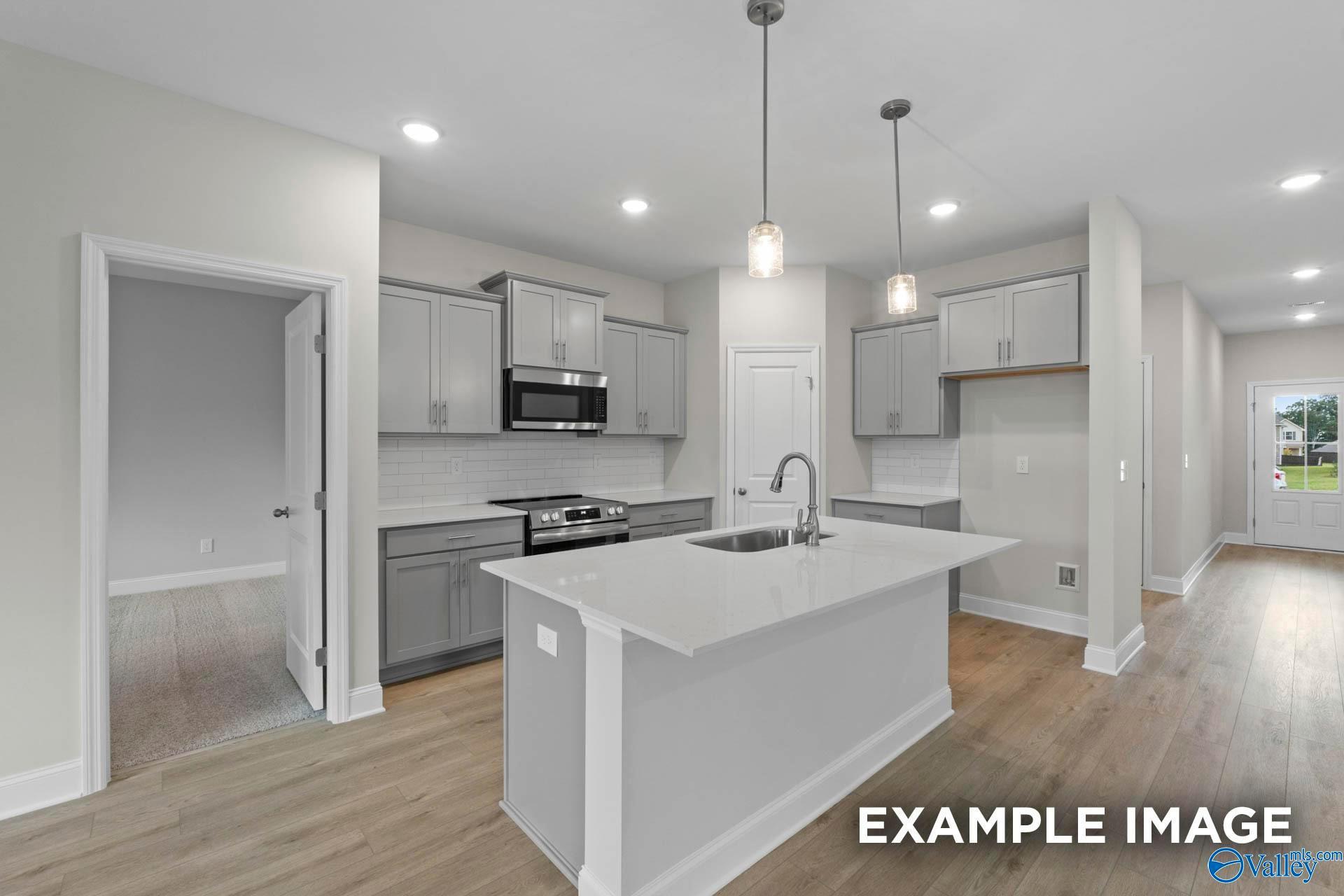 Modern kitchen with gray cabinets, quartz island, and pendant lighting in The Franklin C home, Noble Ridge, Cullman, Alabama.