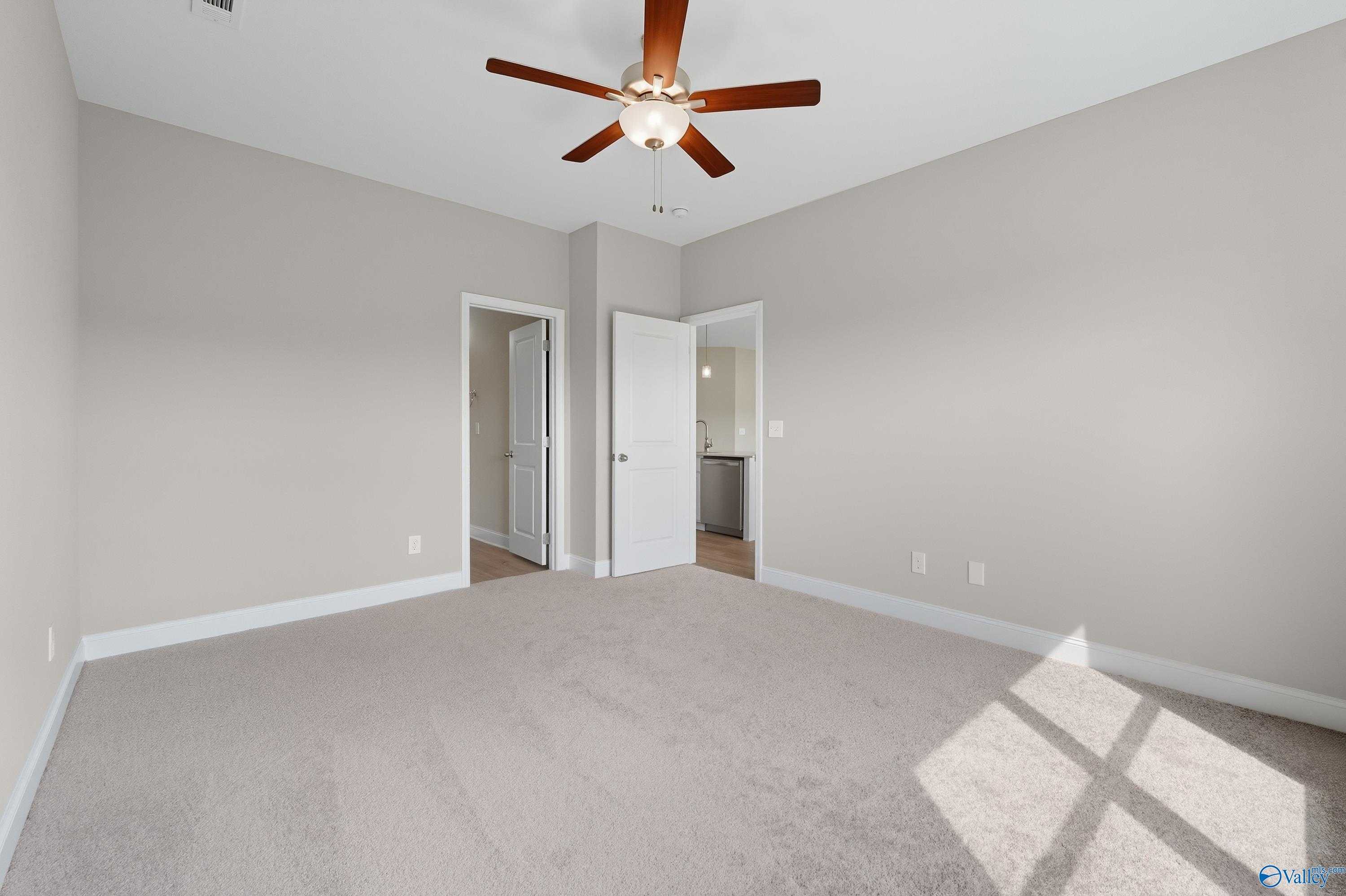 Spacious secondary bedroom featuring ceiling fan, light gray walls, and adjacent bath in Davidson Homes The Franklin, Meridianville, Alabama