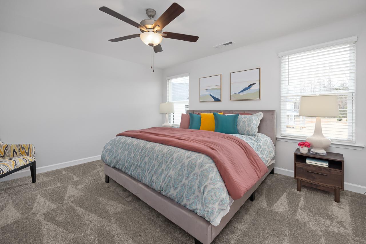 Spacious primary bedroom in Gregory Village Lillington NC by Davidson Homes featuring king bed with colorful bedding and ceiling fan
