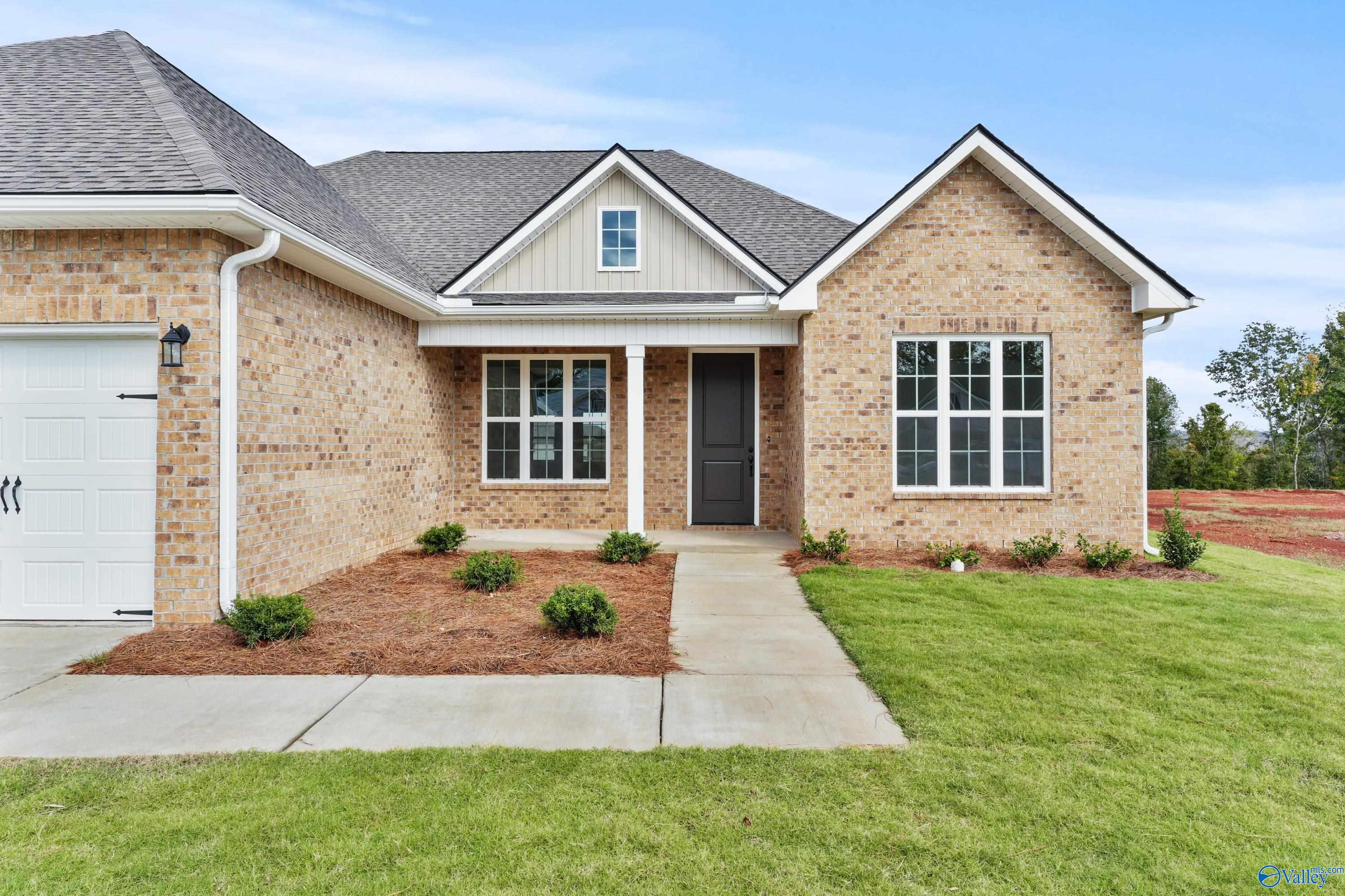 Modern brick 1-story home with 3-car garage, gabled roof, and landscaped front yard in Creekside, Harvest, Alabama