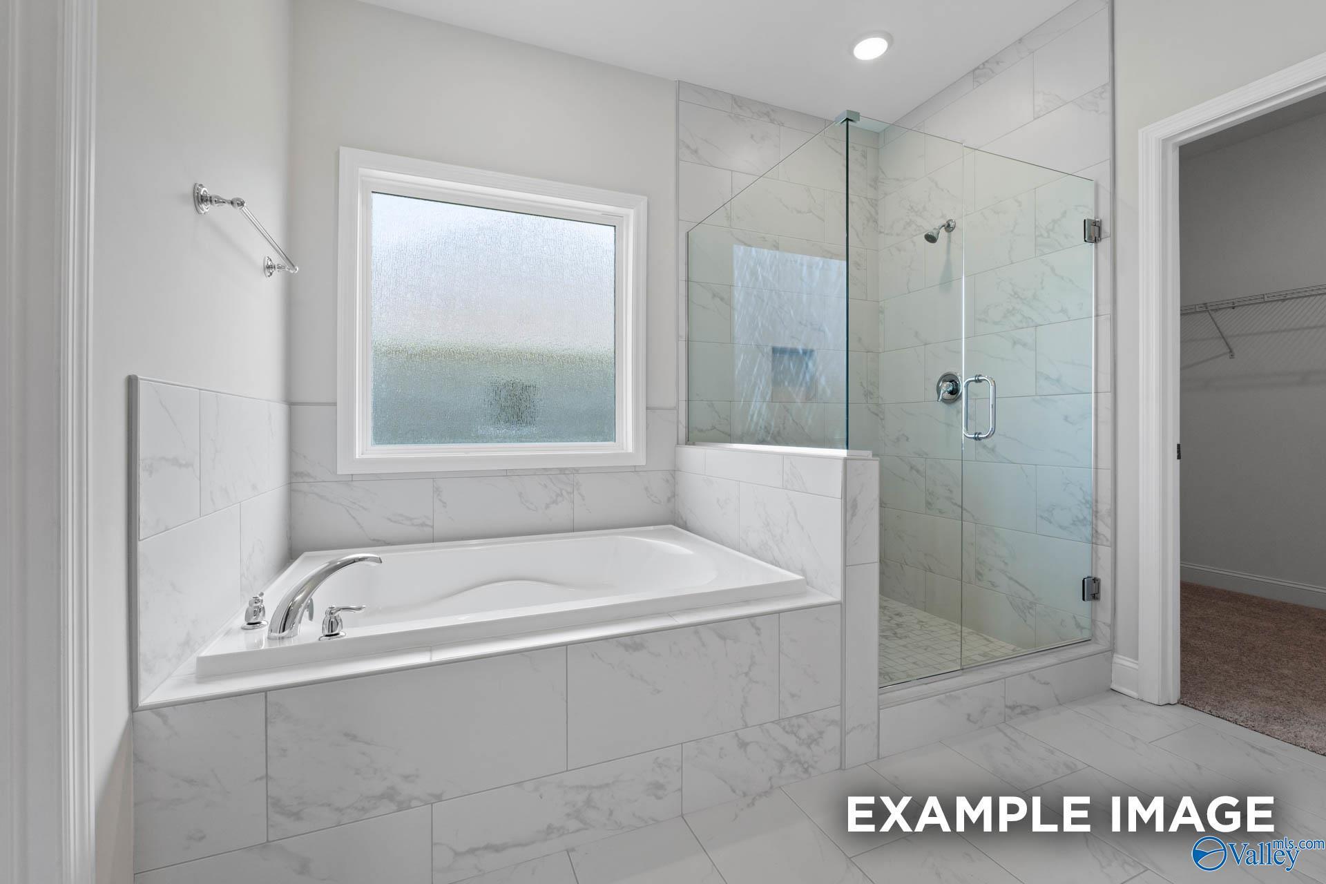 Primary bathroom with soaking tub and walk-in glass shower in The Harrison B floor plan at The Meadows in Athens, Alabama.