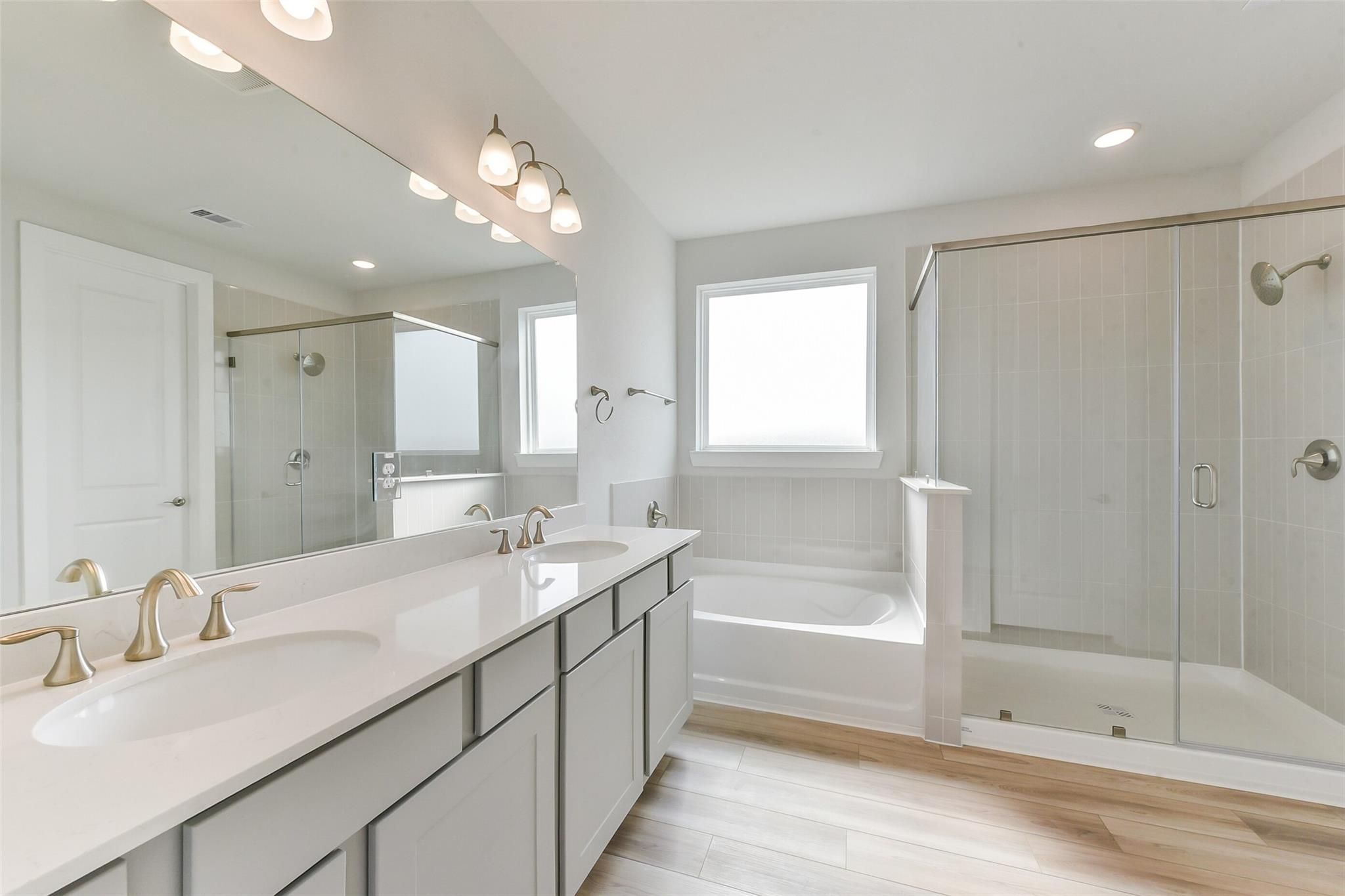 Modern master bathroom with double vanity, soaking tub, and frameless glass shower in Davidson Homes The Edward A, Lago Mar