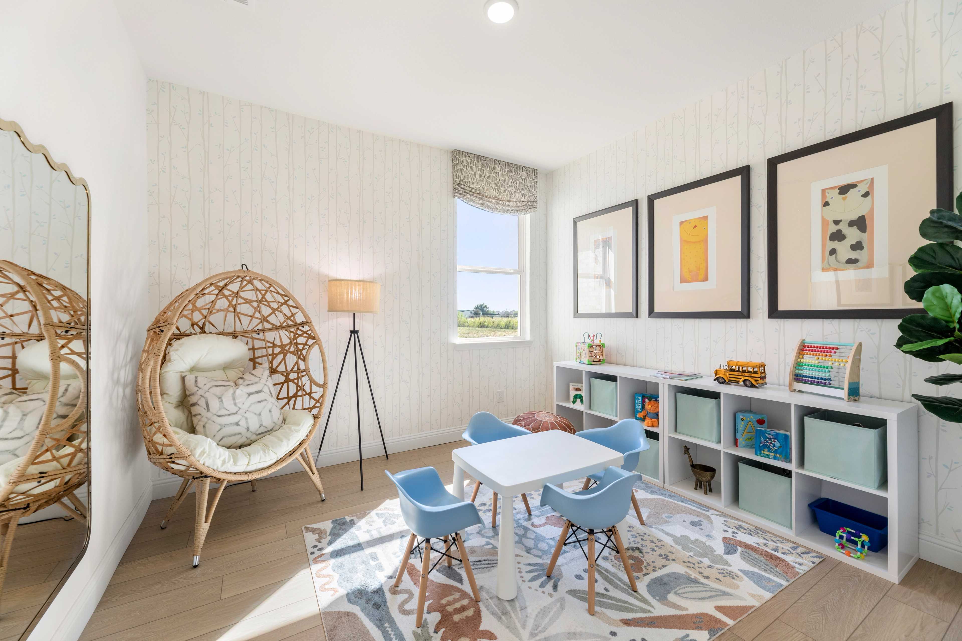 Cozy children's playroom at Meadow Ridge Estates in Josephine TX with woven rattan chairs, kids table, bookshelves, and shiplap walls