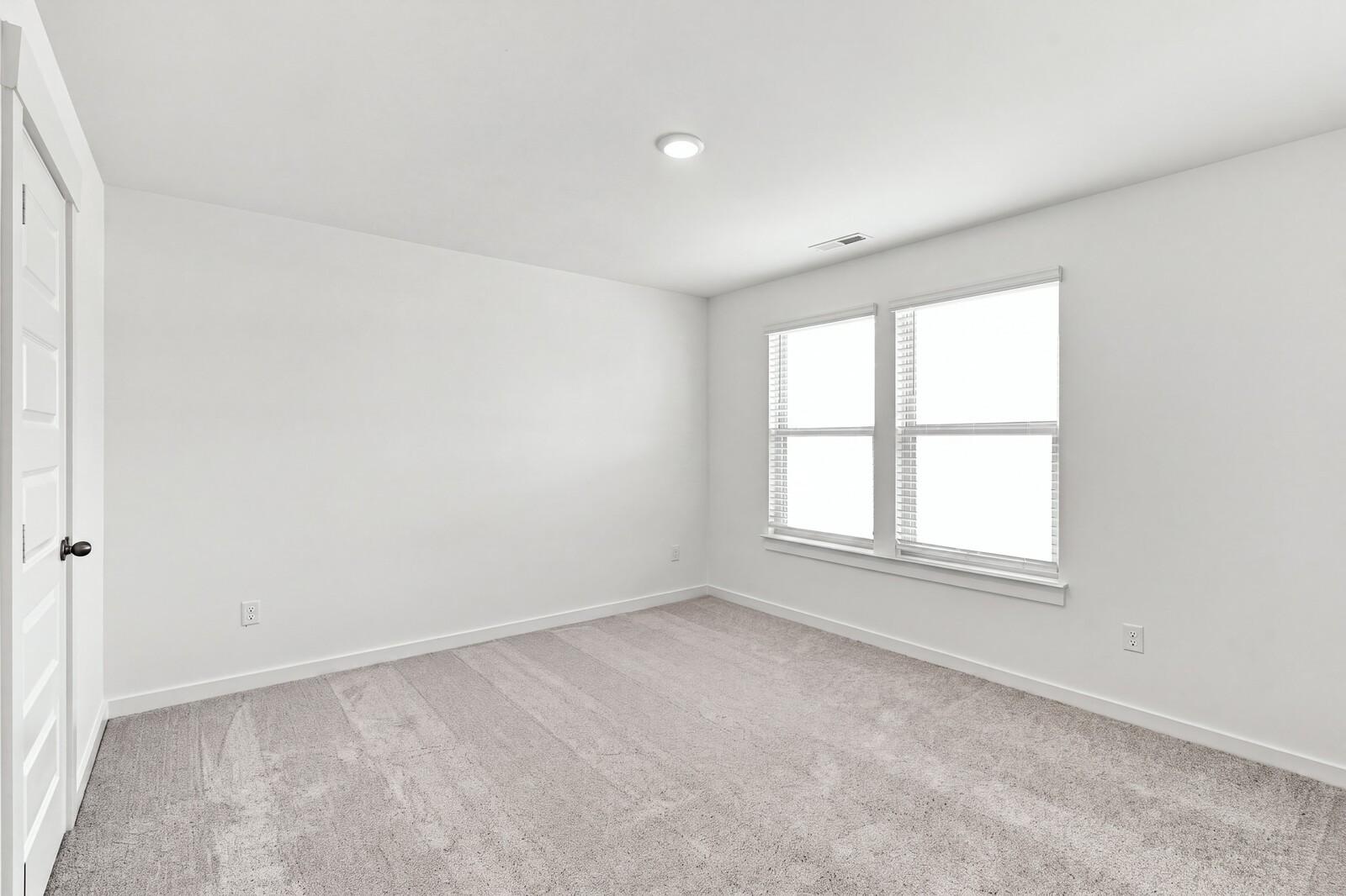 Bright carpeted bedroom with double windows in The Willow C floor plan by Davidson Homes, Woods Crossing, Gallatin, TN