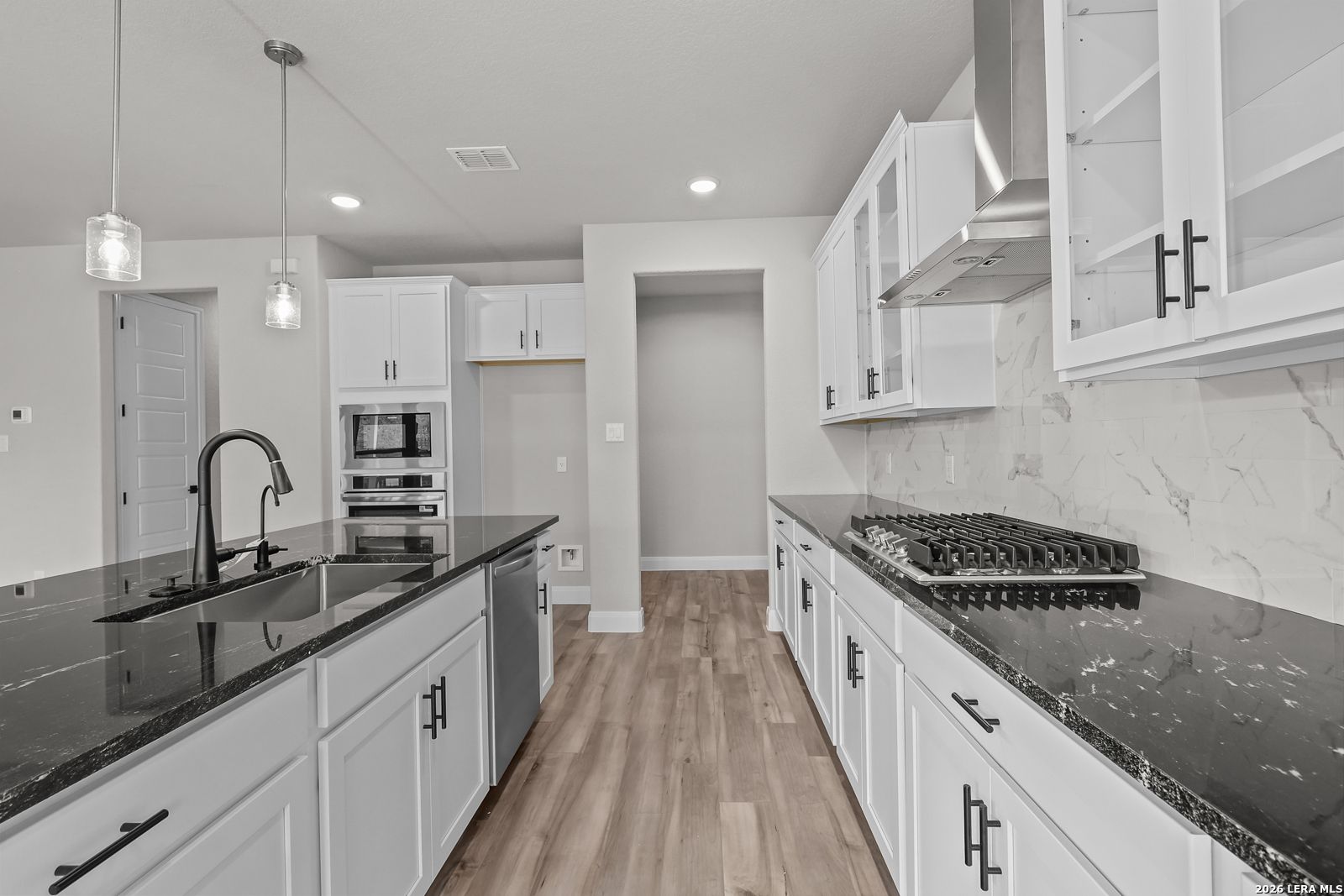 Modern kitchen with white cabinets, black granite island, stainless appliances, gas range in The Belmont H, Castroville TX