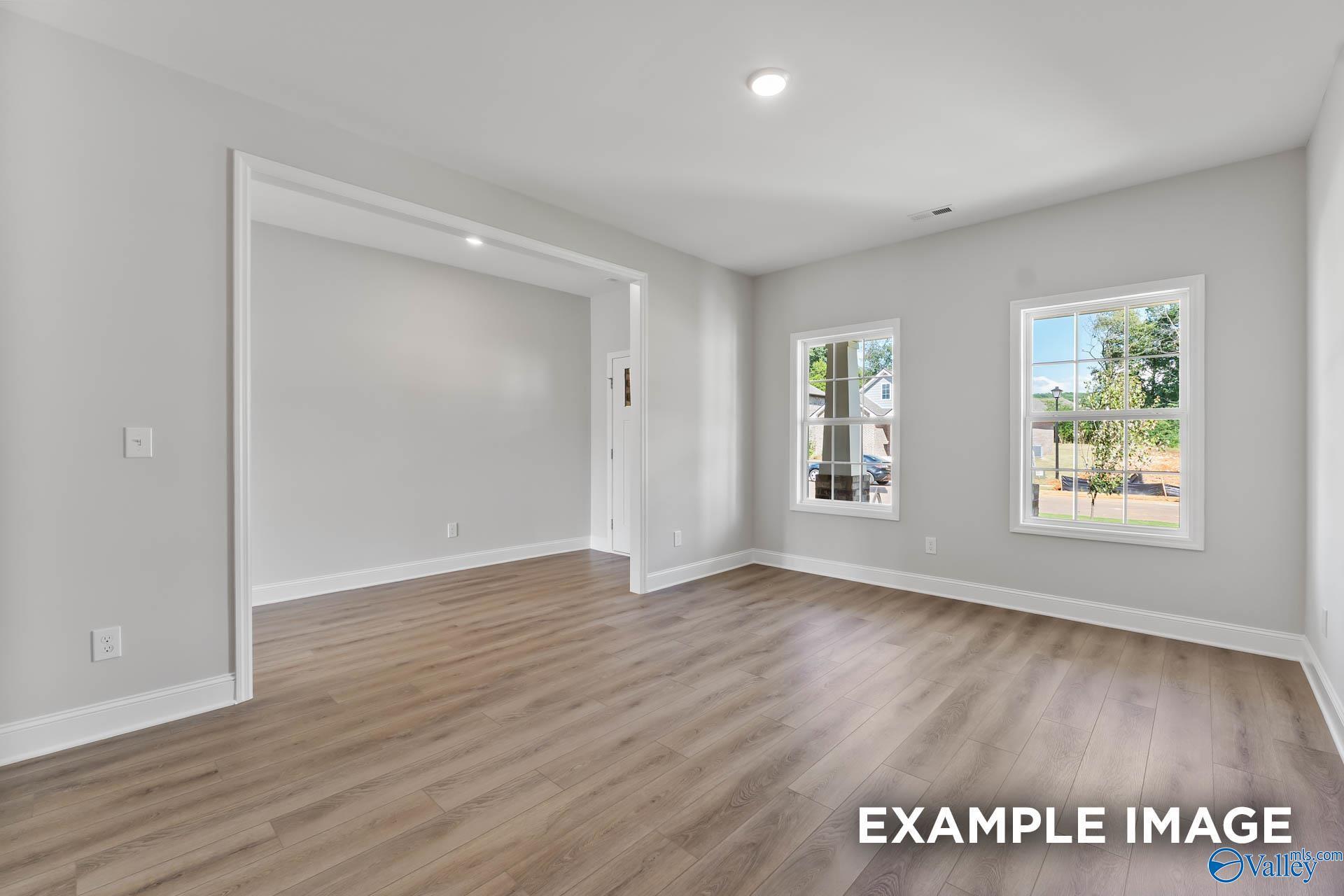 Bright, spacious living area with wood-look flooring in The Chelsea D floor plan at Berry Cove, New Market, Alabama.