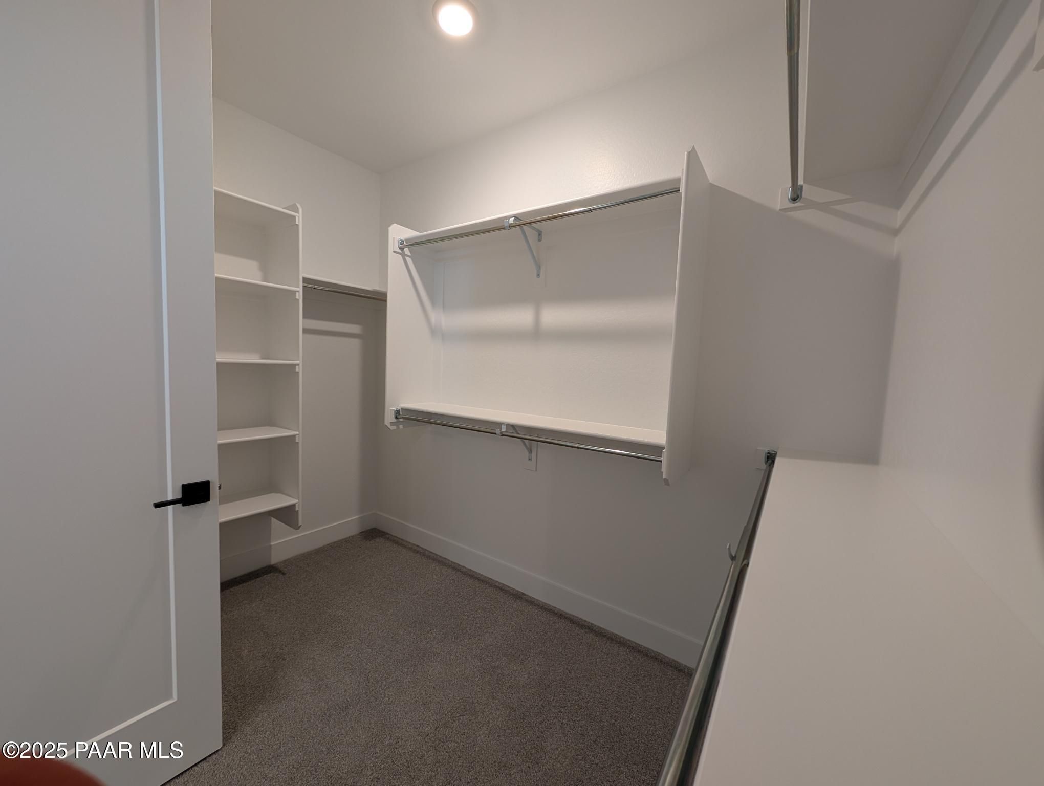 Spacious walk-in closet with white built-in shelves and hanging rods in Davidson Homes The Sheridan II F, Prescott, Arizona