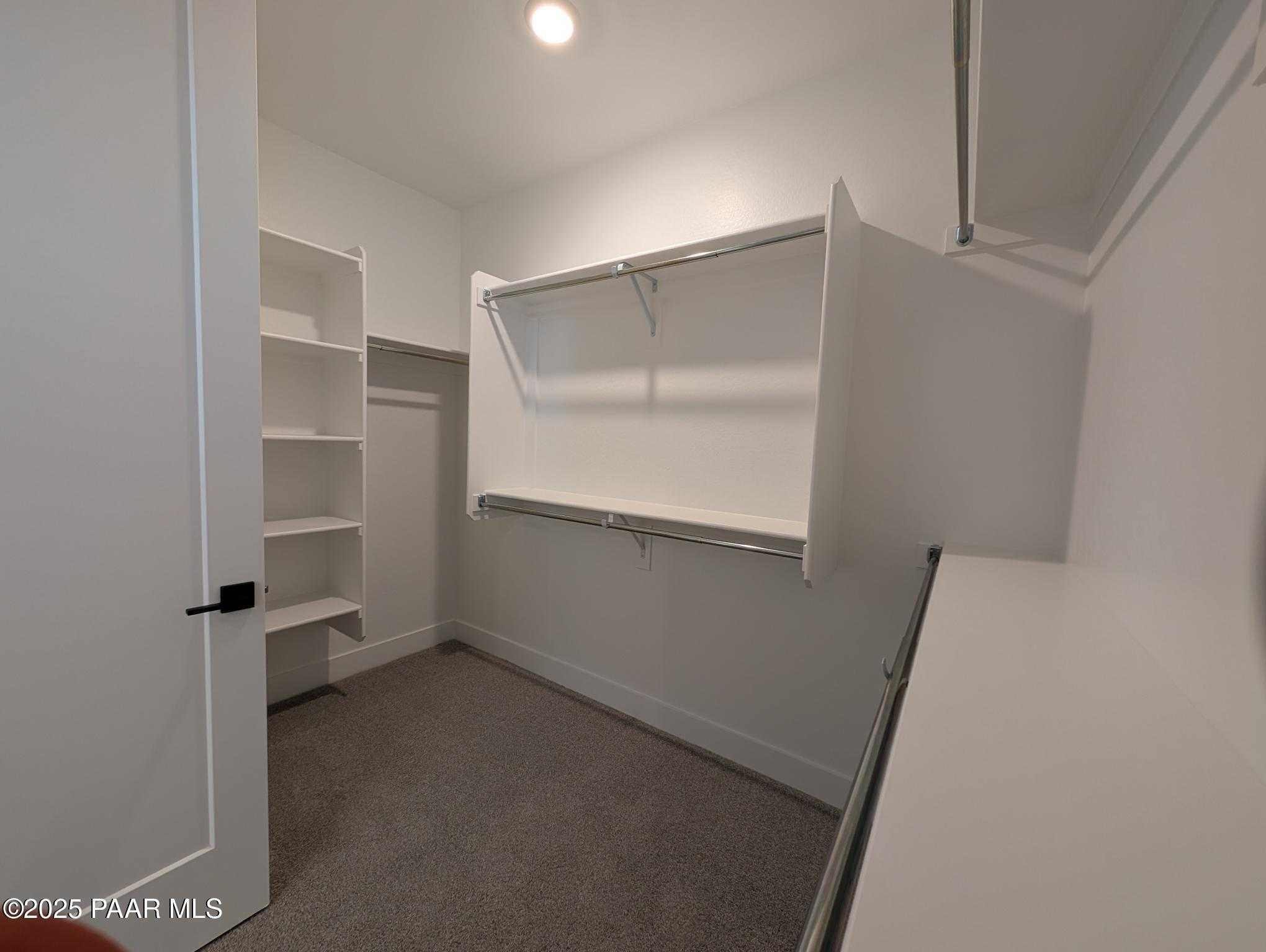 Spacious walk-in closet with white built-in shelves and hanging rods in Davidson Homes The Sheridan II F, Prescott, Arizona