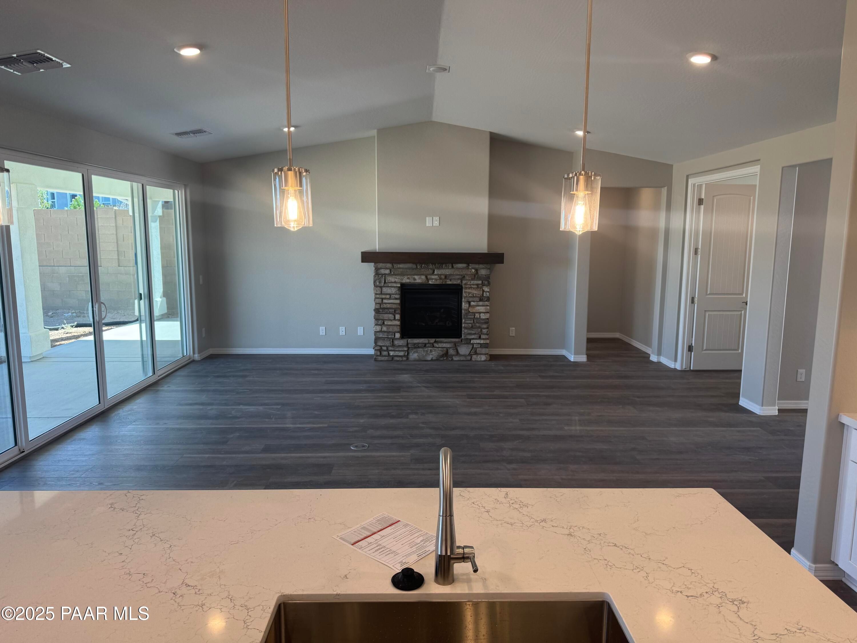 Spacious great room with stacked stone fireplace, pendant lights, and quartz kitchen island in Davidson Homes The Monarch E, Prescott AZ