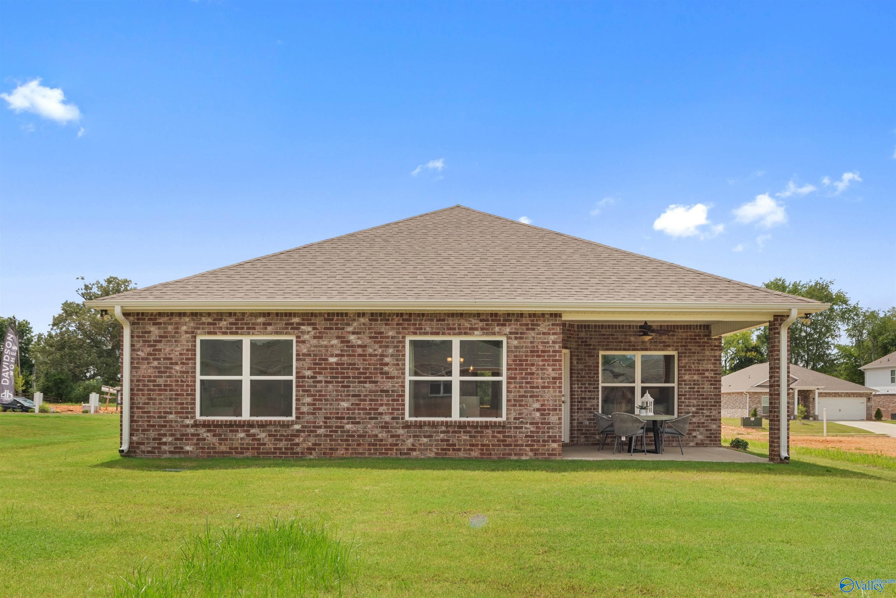 Brick one-story Everett home by Davidson Homes featuring covered porch, brick facade, and lush green yard in Flint Meadows, New Market, Alabama