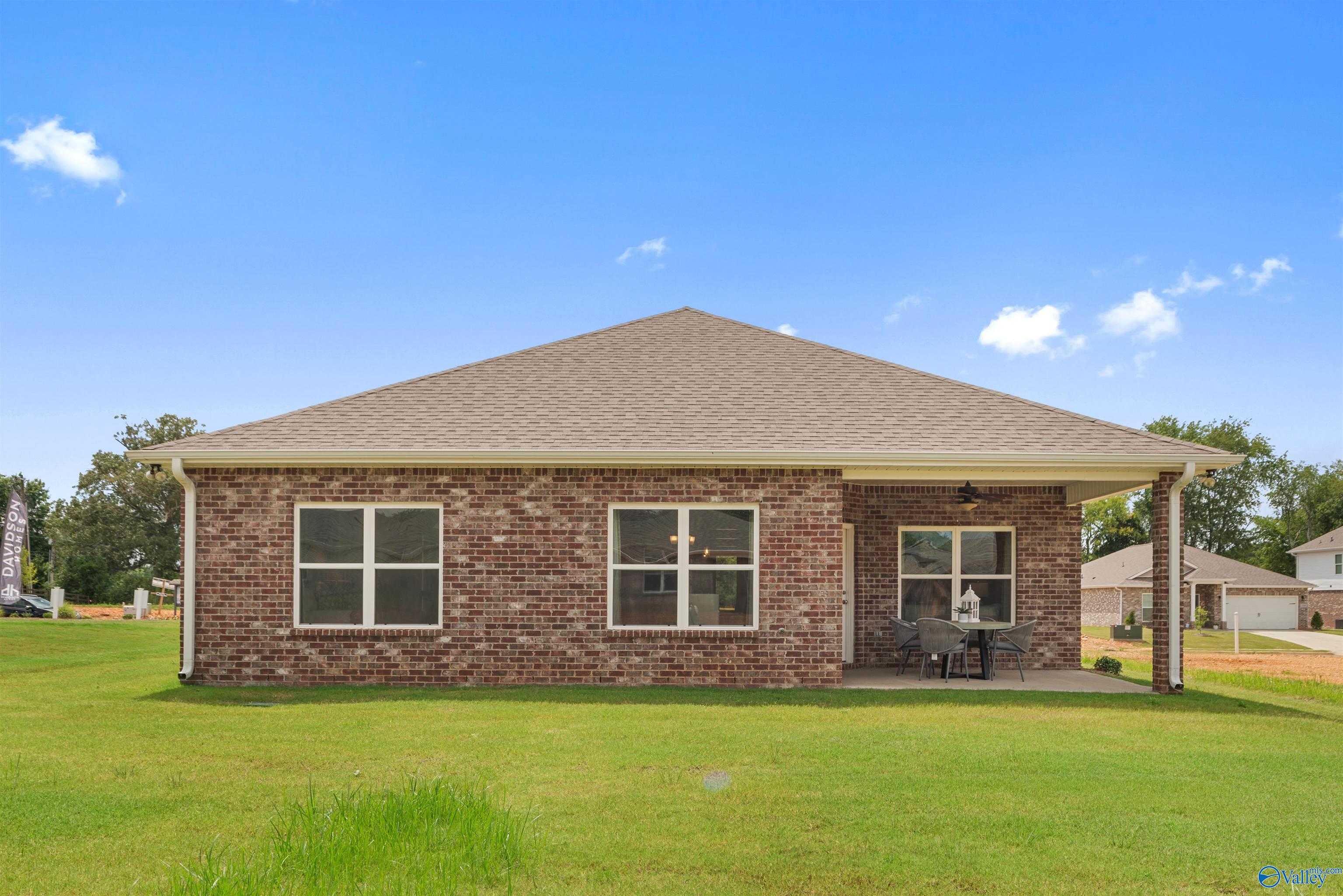 Brick one-story Everett home by Davidson Homes featuring covered porch, brick facade, and lush green yard in Flint Meadows, New Market, Alabama