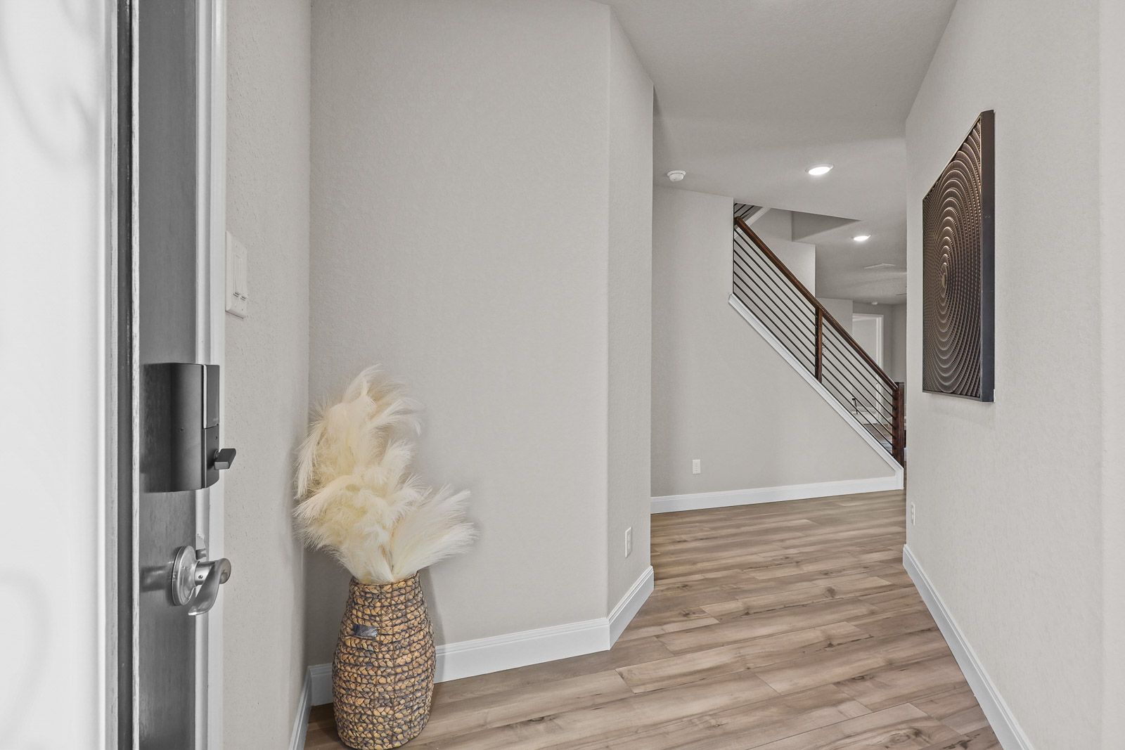 Bright entryway of The Jennings F floor plan featuring wide-plank wood flooring and a modern staircase with iron railing.