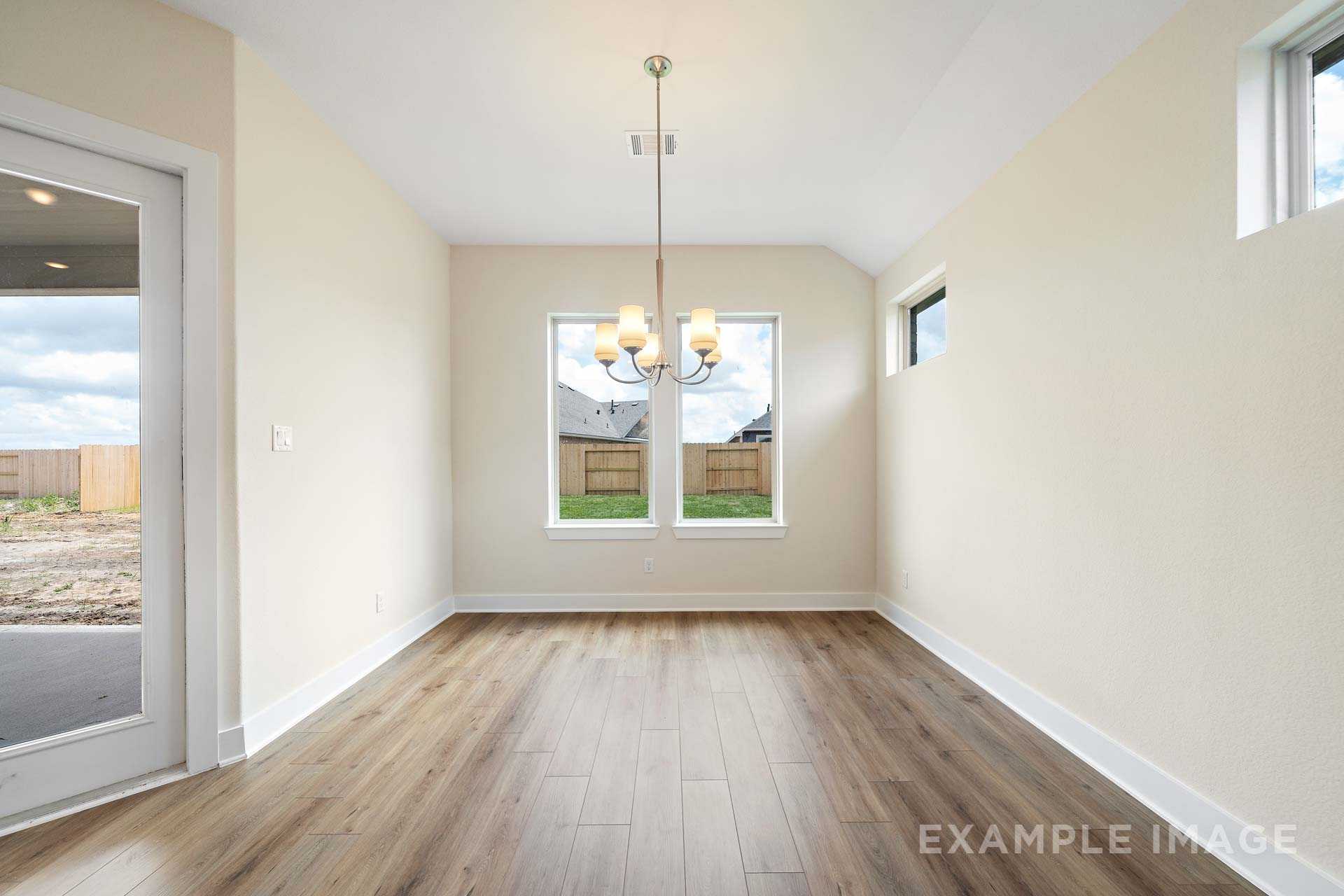 Spacious dining room in The Diana C home with beige walls, hardwood floors, large windows, and modern chandelier