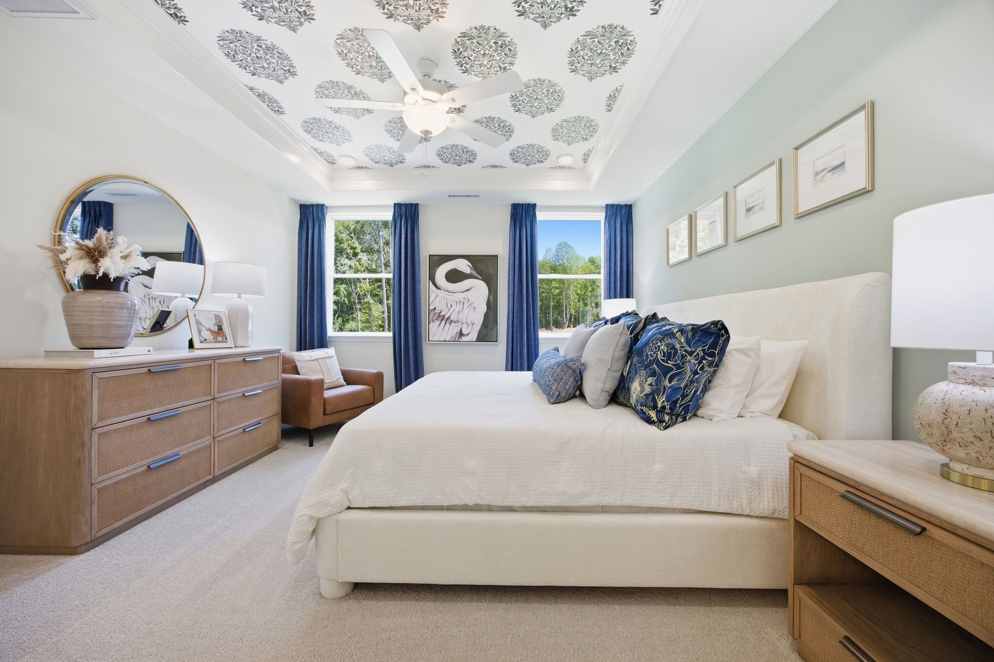 Spacious master suite in The Ashport featuring a tray ceiling with patterned wallpaper and elegant blue and neutral decor.