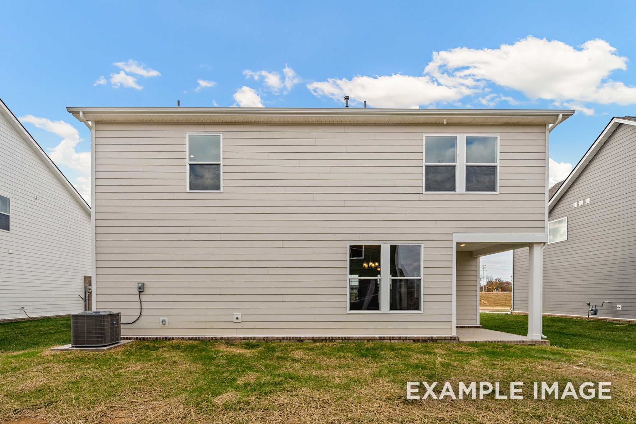 Rear elevation of The Murray A 2-story home by Davidson Homes, beige siding, covered patio, large windows, grassy yard in White House TN