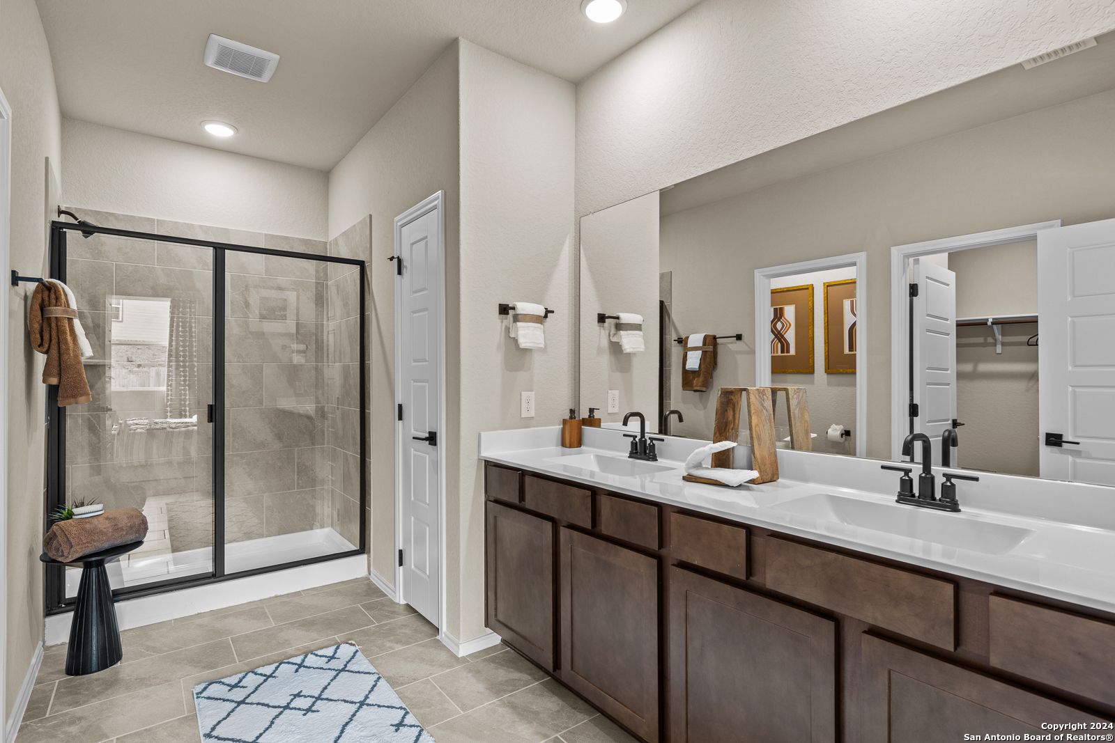 Modern master bathroom with double vanity, glass walk-in shower, and wood cabinets in Davidson Homes The Douglas F, San Antonio