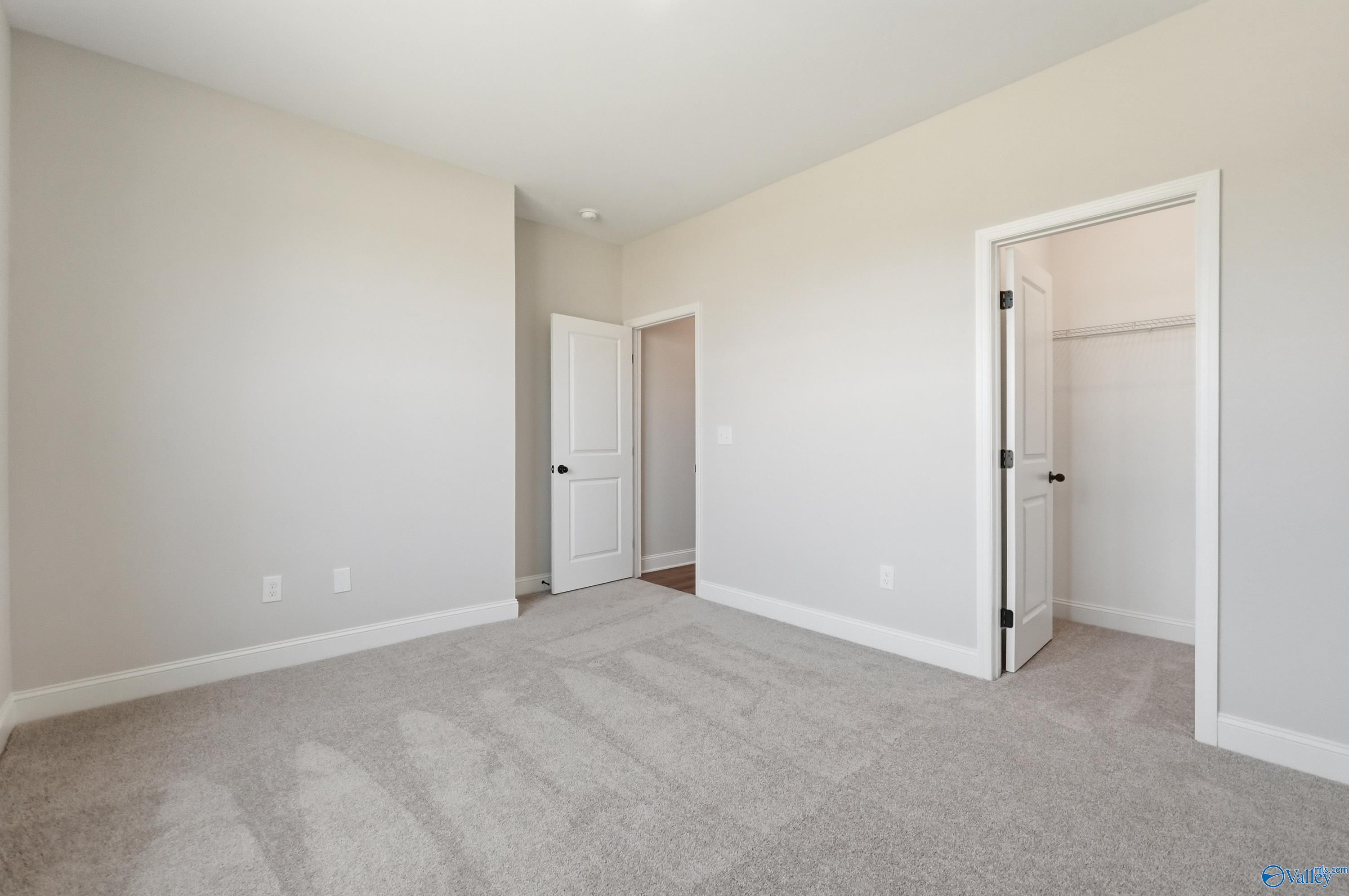 Spacious empty bedroom with open walk-in closet and en-suite door in Davidson Homes The Rockford B, Athens AL