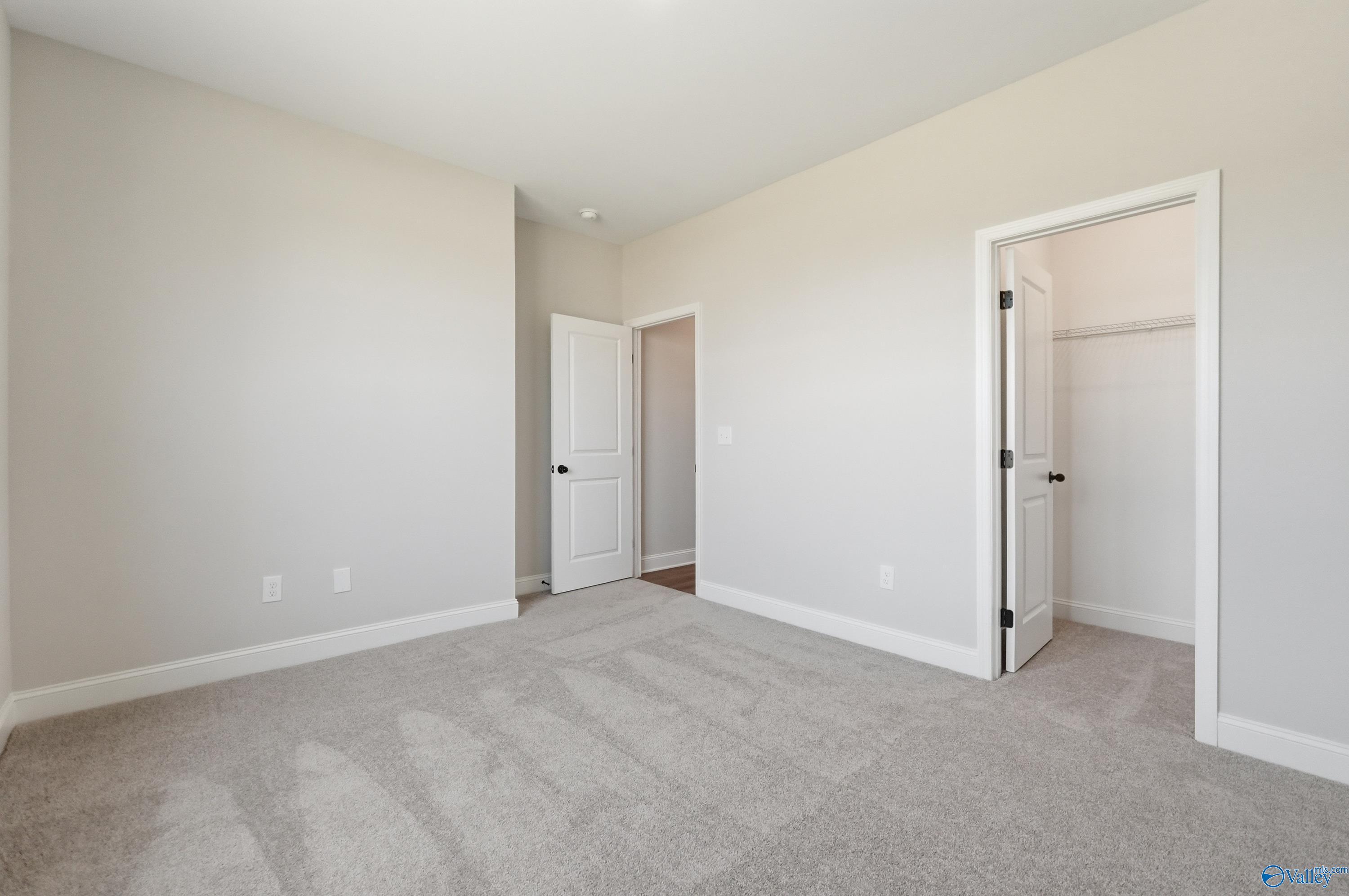 Spacious empty bedroom with open walk-in closet and en-suite door in Davidson Homes The Rockford B, Athens AL
