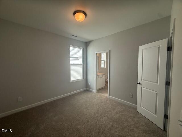 Bright bedroom with gray walls, neutral carpet, blinds-covered window, and attached bath in The Daphne C, Zebulon, NC