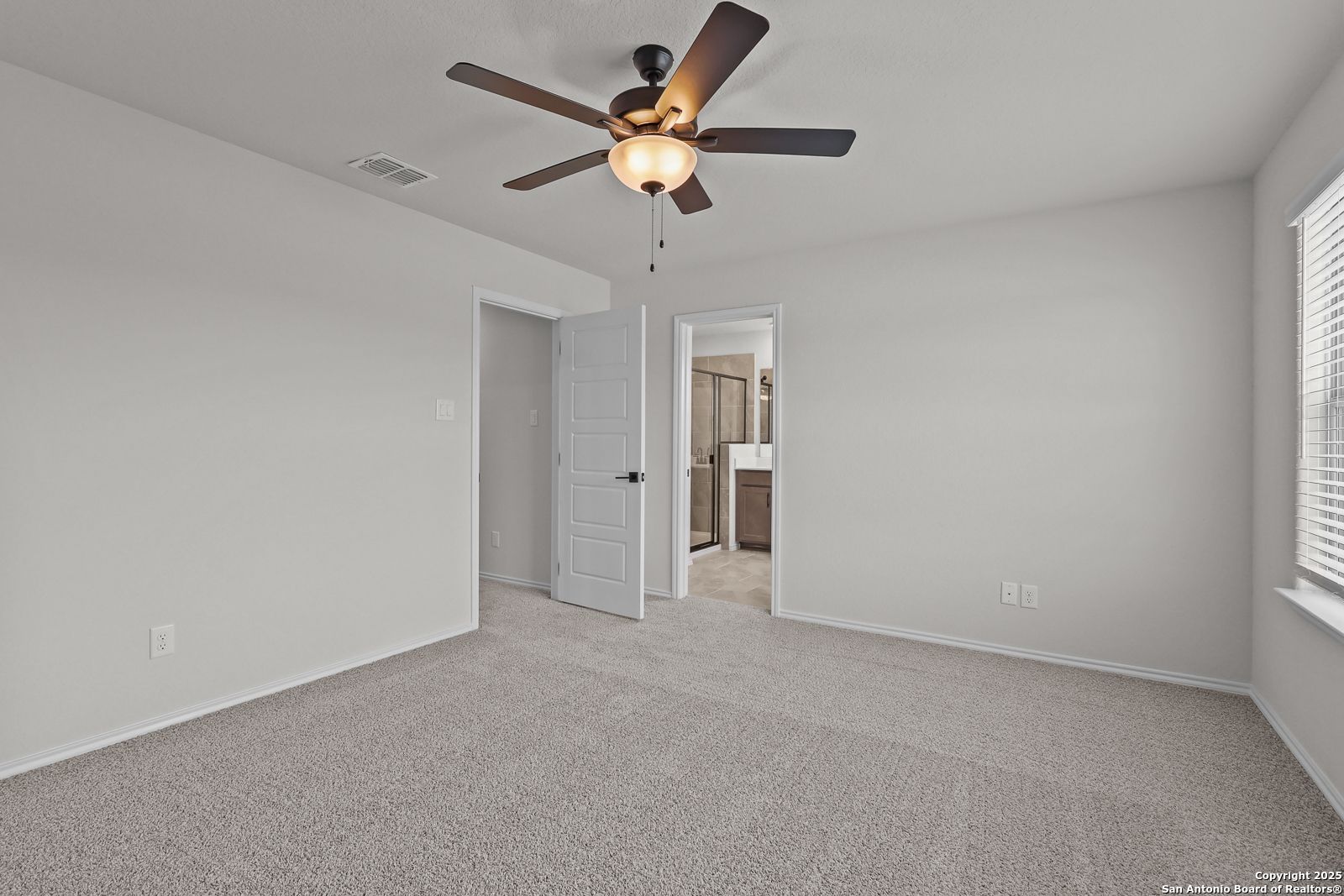 Bright secondary bedroom with ceiling fan, carpet floors, and attached bath in Davidson Homes The Florence C, San Antonio