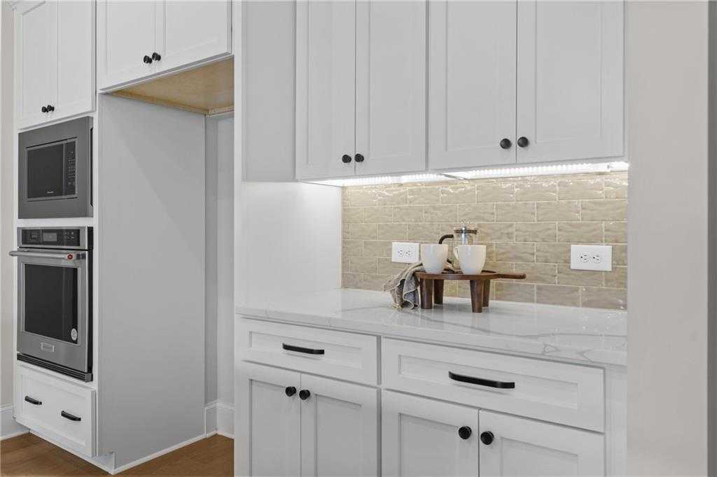 Modern white kitchen with shaker cabinets, double wall ovens, quartz counters, subway tile backsplash in Davidson Homes Seaside B, Woodstock GA