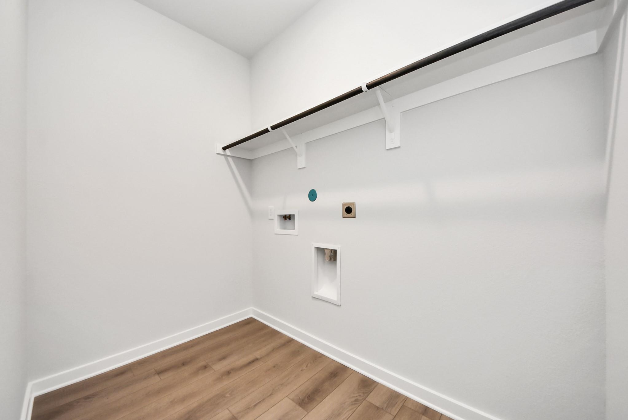 Dedicated laundry room with washer and dryer hookups and overhead shelving in Davidson Homes The Daphne F, Crosby, Texas.