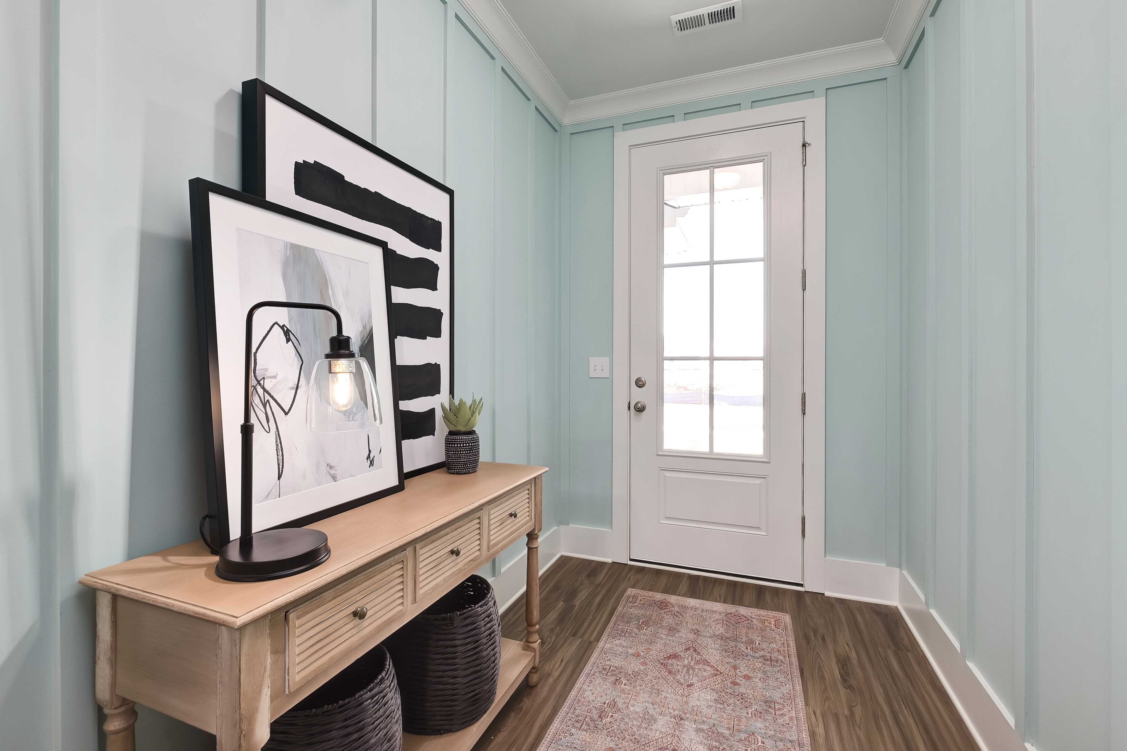 Elegant entry foyer at Mallard Landing in Athens Alabama with light blue shiplap walls, white French door, console table, abstract art, and hardwood floors