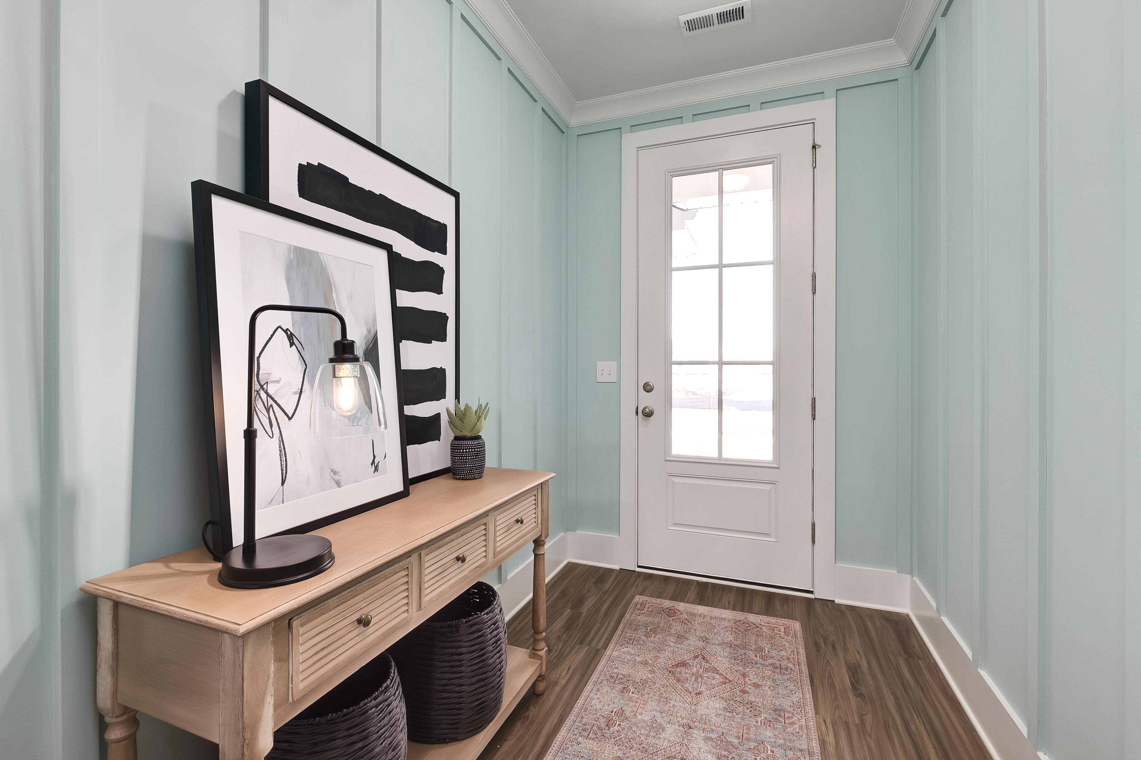 Elegant entry foyer at Mallard Landing in Athens Alabama with light blue shiplap walls, white French door, console table, abstract art, and hardwood floors