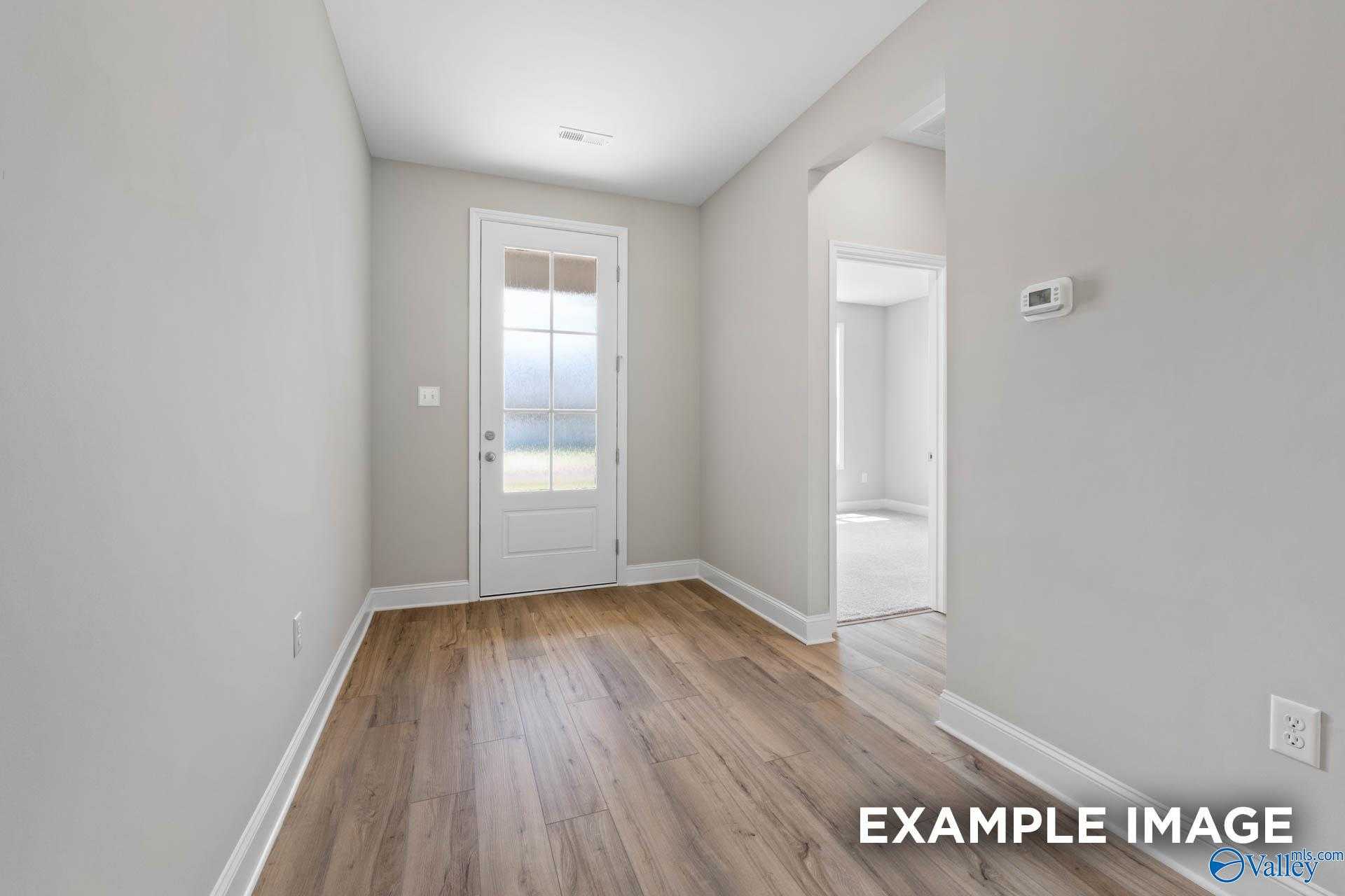 Bright hallway with hardwood floors, glass-paneled door, and archway in Davidson Homes The Montgomery, Meridianville, Alabama