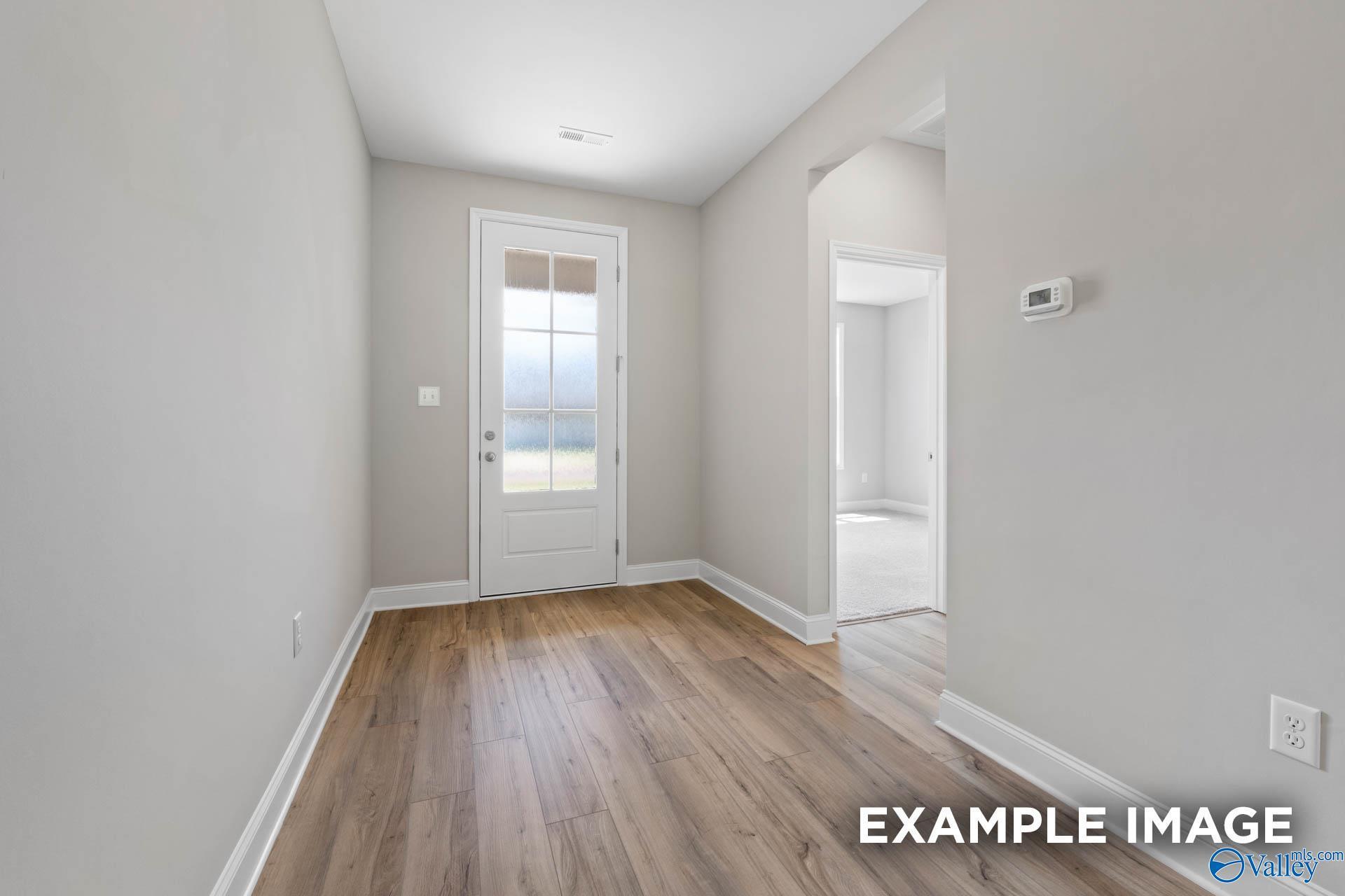 Bright hallway with hardwood floors, glass-paneled door, and archway in Davidson Homes The Montgomery, Meridianville, Alabama