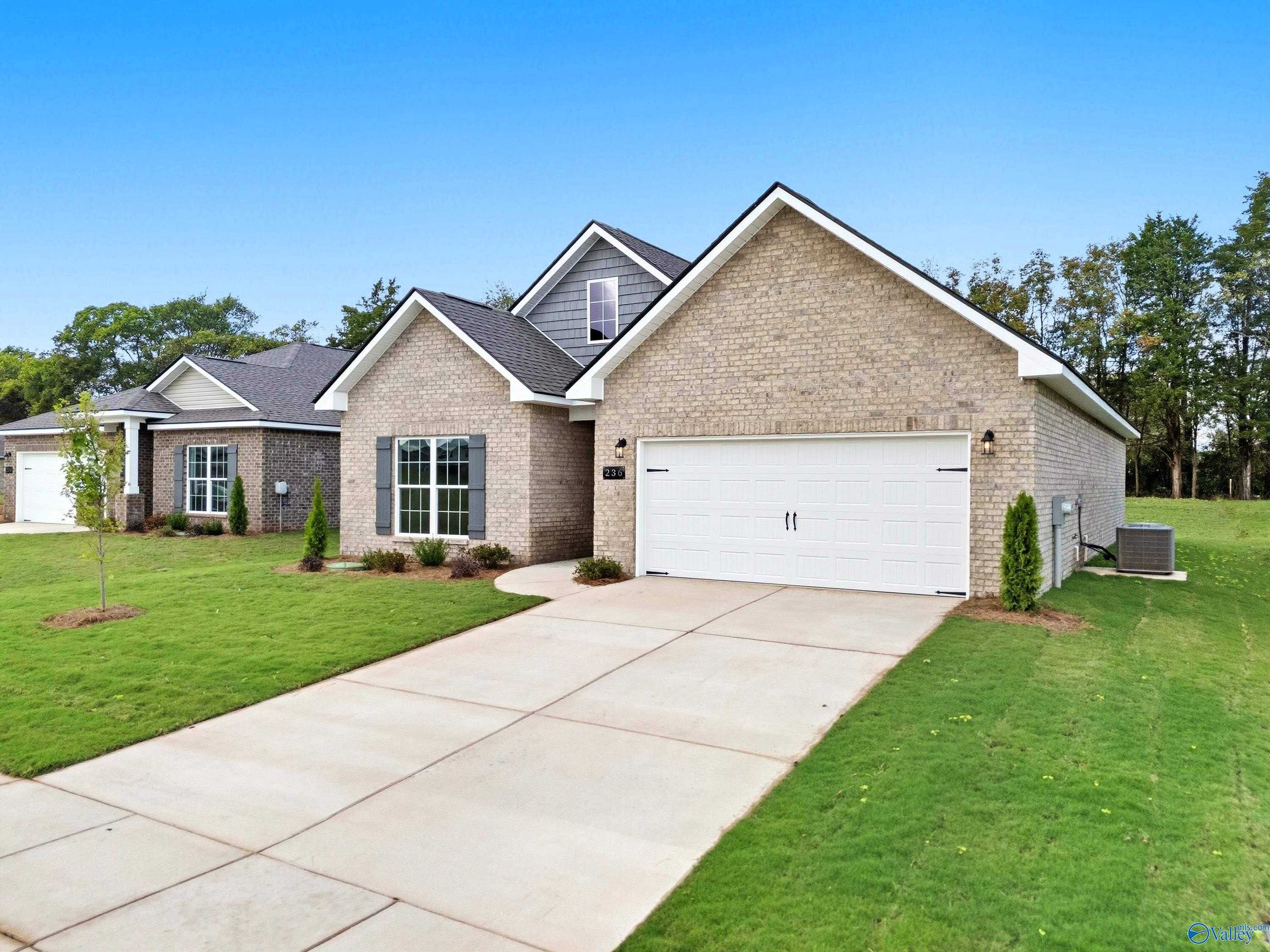 Modern beige brick single-story home with 2-car garage, driveway, and lush green lawn in Lynn Meadows, Meridianville, Alabama - Davidson Homes The Franklin C