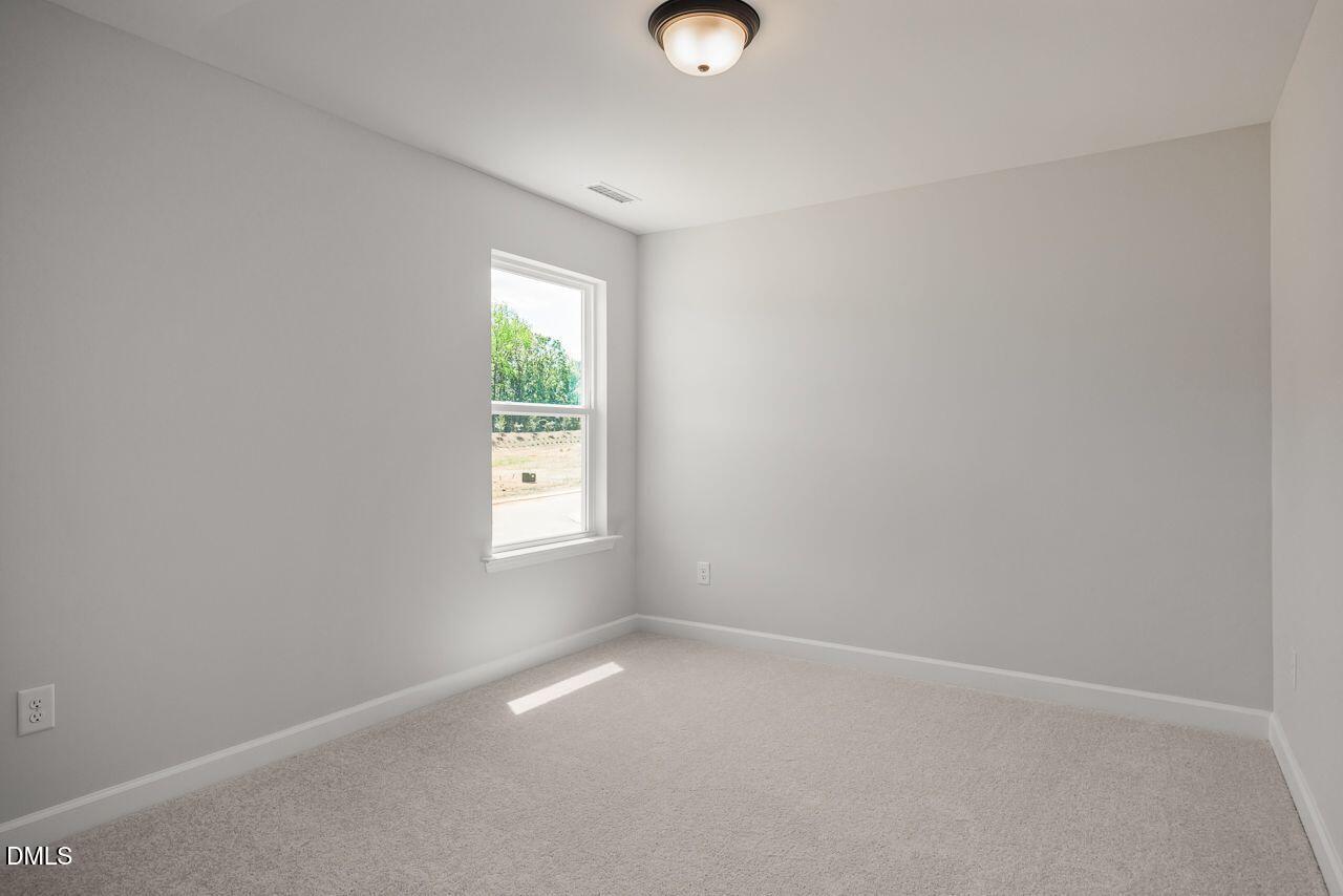 Bright, neutral-toned bedroom with plush carpeting in The Birch II A floor plan at Montrose in Aberdeen, North Carolina.