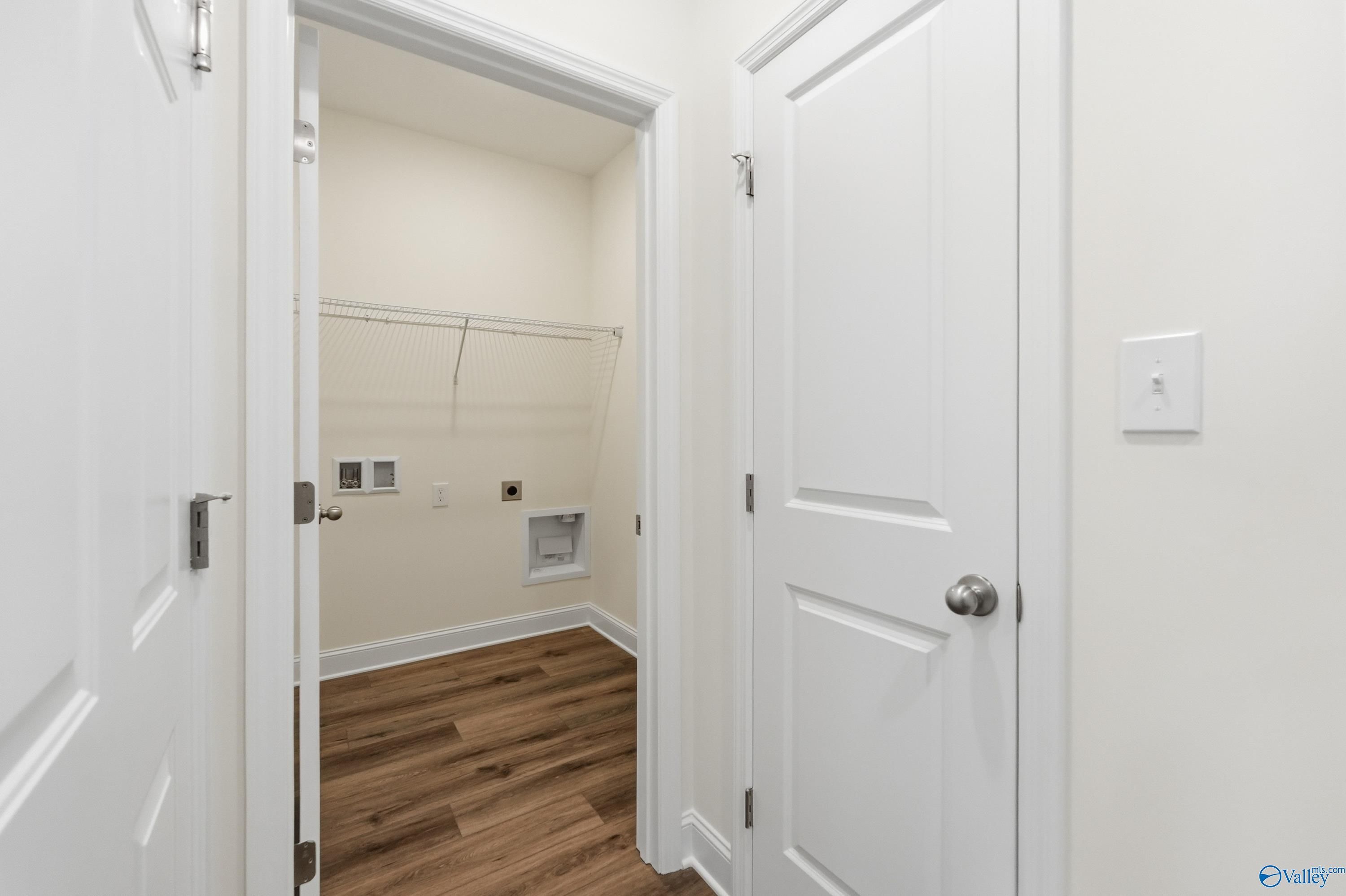 Bright laundry room with washer/dryer hookups, closet storage, and hardwood floors in The Asheville C, Davidson Homes, Meridianville AL