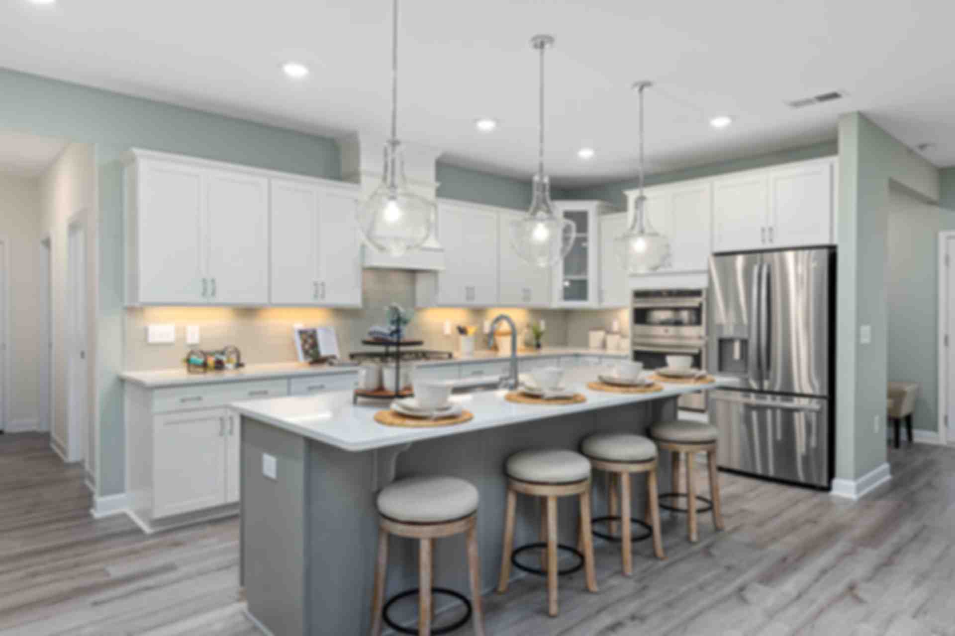 Spacious modern kitchen at Weatherford East in Angier NC with white cabinets, gray island, stainless appliances, hardwood floors
