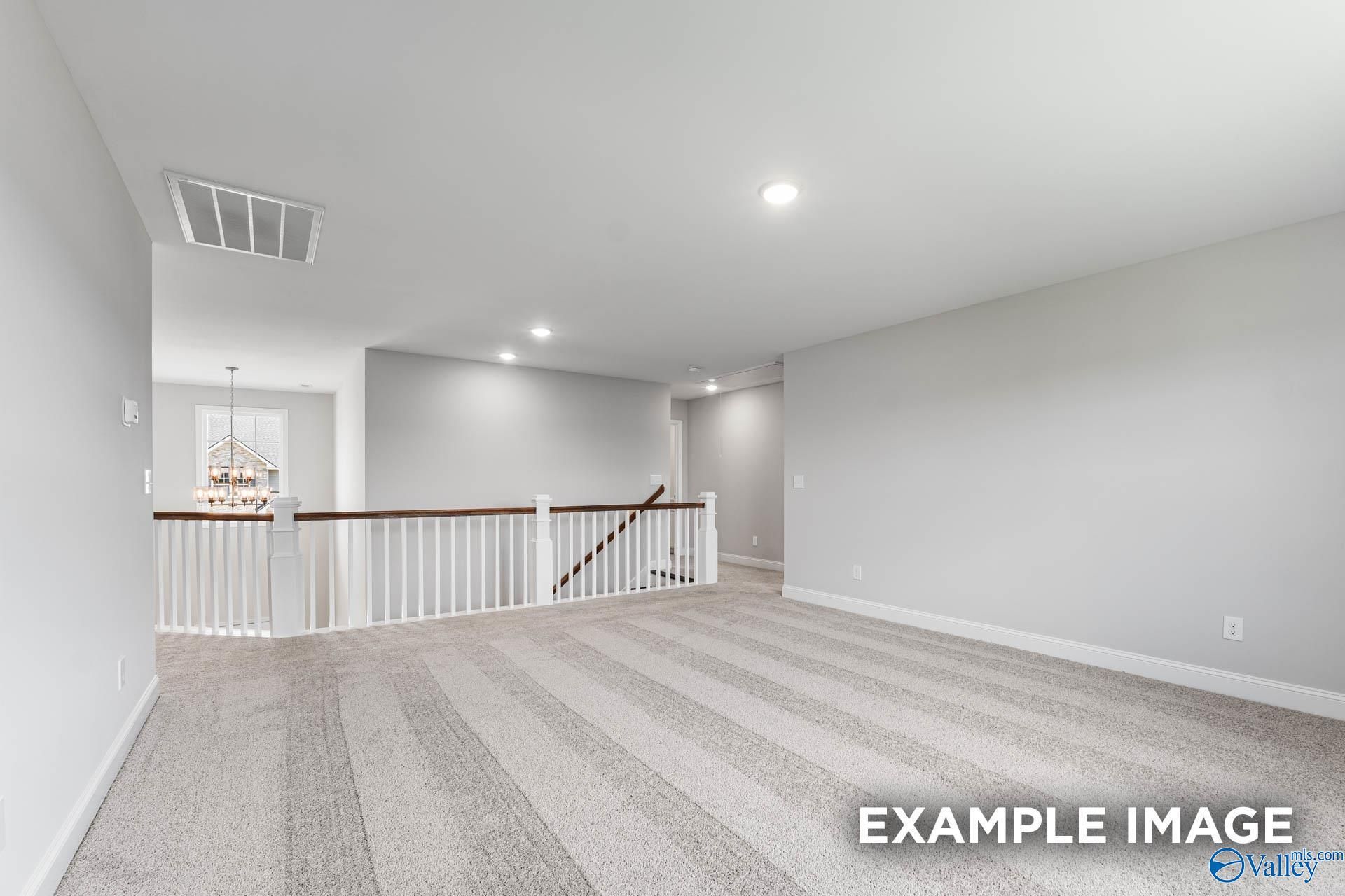 Spacious upstairs loft with white balcony railing, chandelier, and gray walls in Evermore Homes Madison D, Madison, Alabama