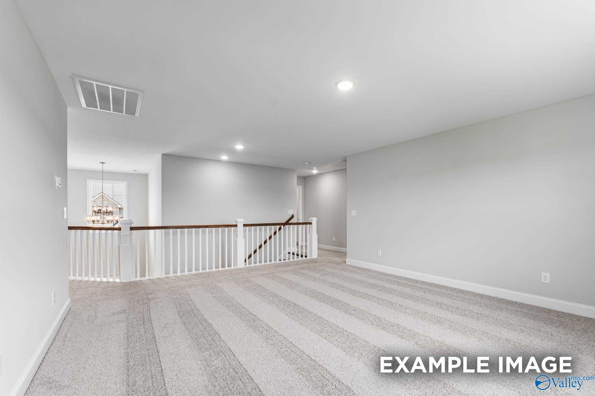 Spacious upstairs loft with gray walls, white railing, chandelier, and carpeted floor in Davidson Homes The Madison A, Harvest, Alabama