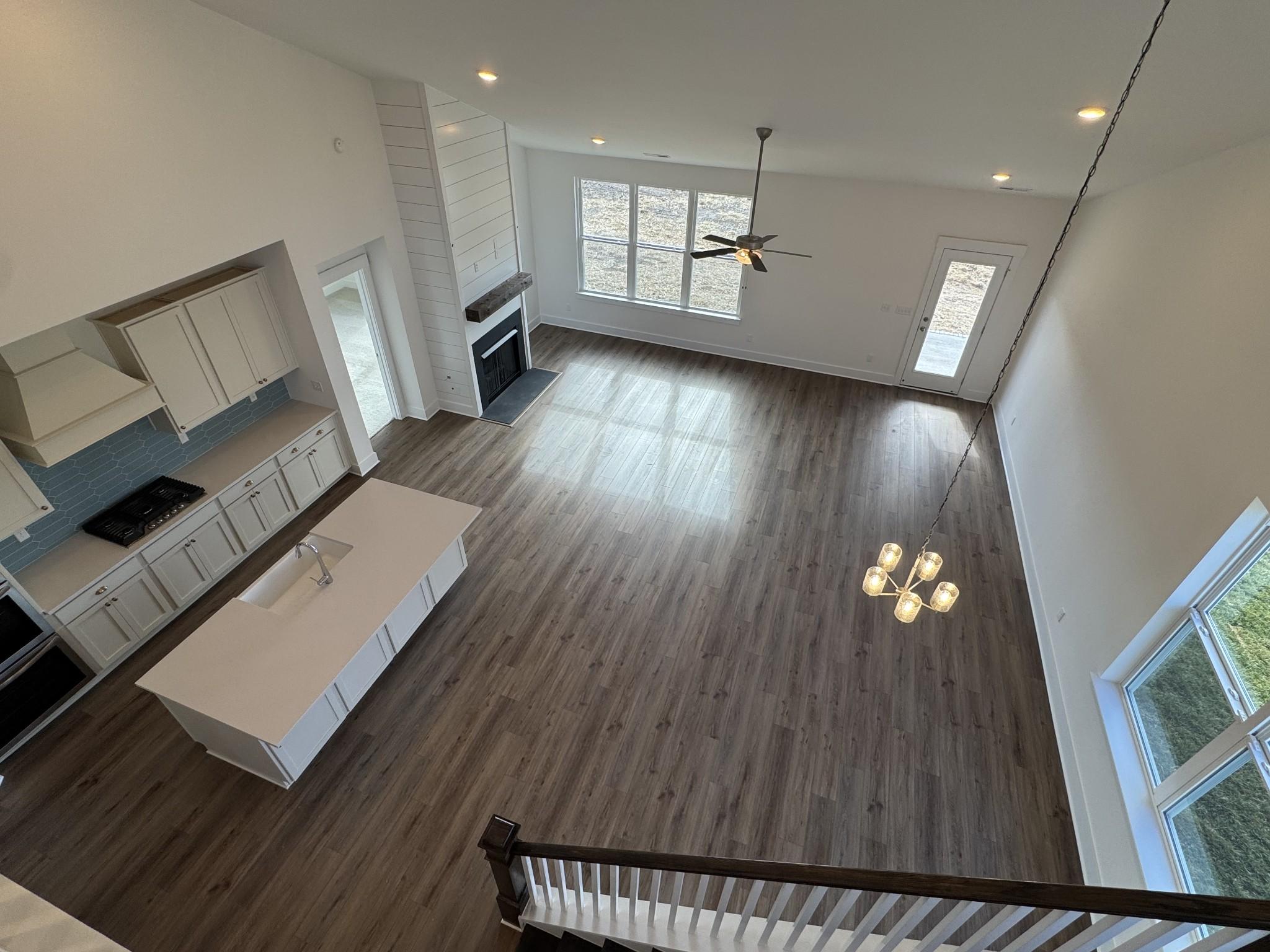 Open-concept kitchen and living room with white island, fireplace, hardwood floors, and staircase in Davidson Homes The Ridgeport, Gallatin, TN