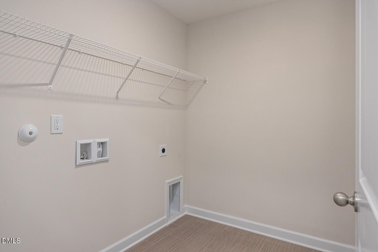 Functional laundry room with wire shelving, washer/dryer hookups, and pet door in Davidson Homes The Preston A, Lillington, NC