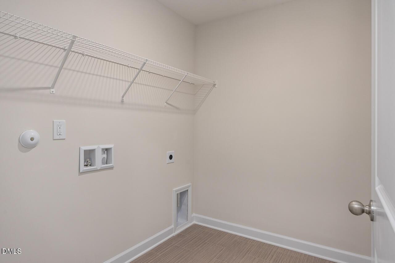 Functional laundry room with wire shelving, washer/dryer hookups, and pet door in Davidson Homes The Preston A, Lillington, NC