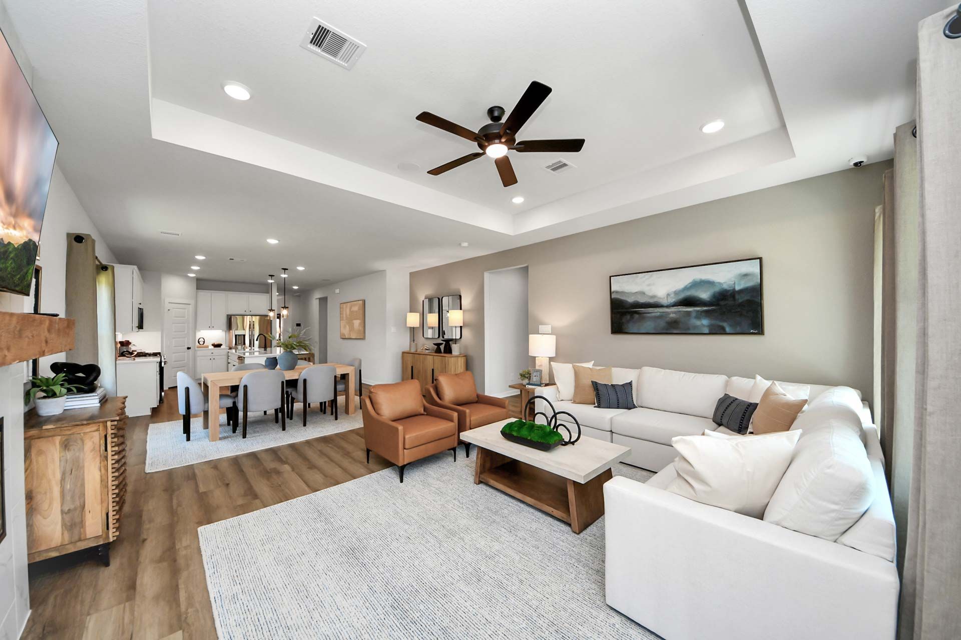 Open-concept living and dining area at Enclave at Newport in Crosby, TX, featuring a tray ceiling and modern farmhouse decor.