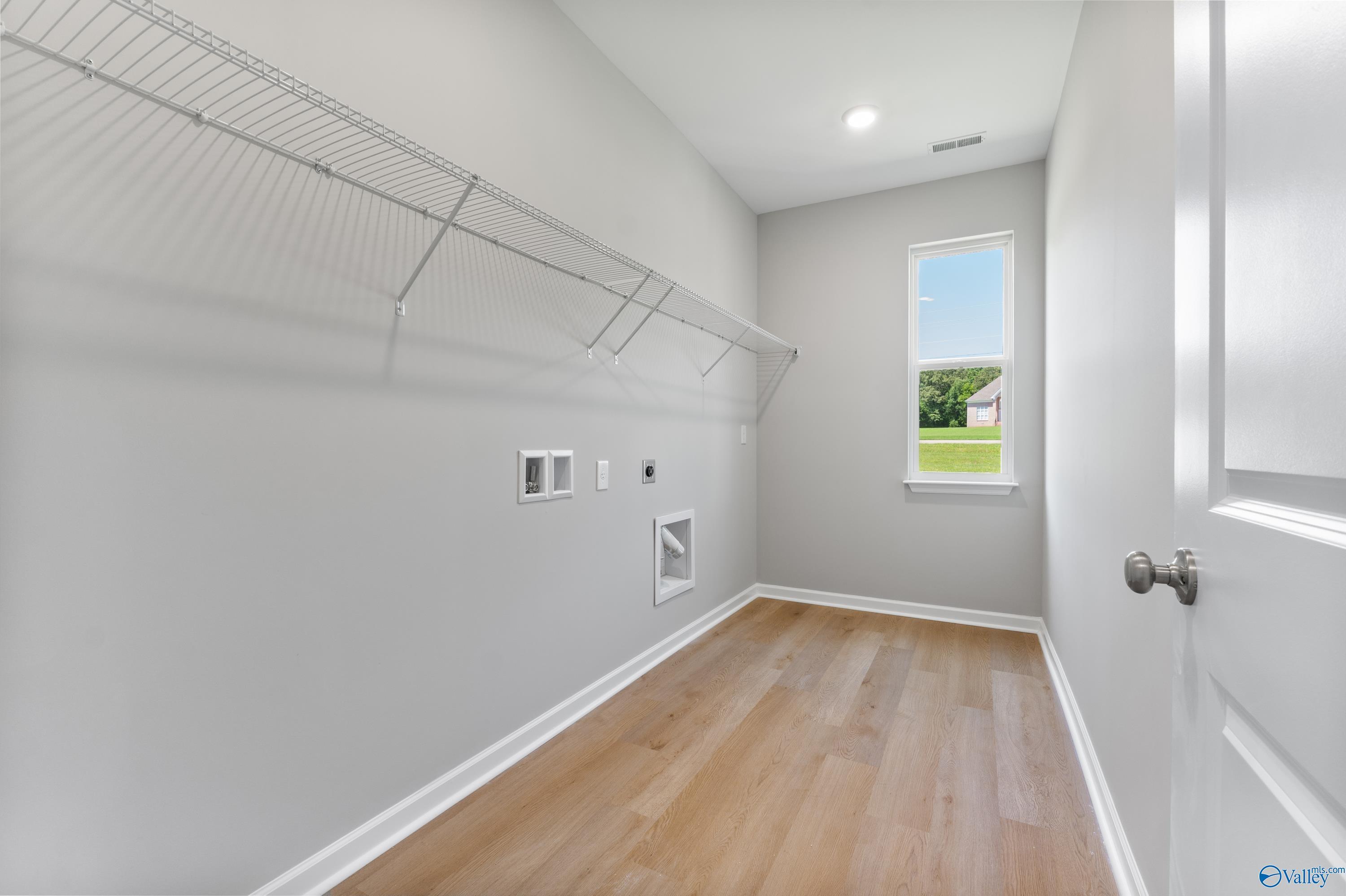 Spacious laundry room with wire shelving, washer/dryer hookups, and window view in Davidson Homes The Charm, Riverton Preserve, Huntsville