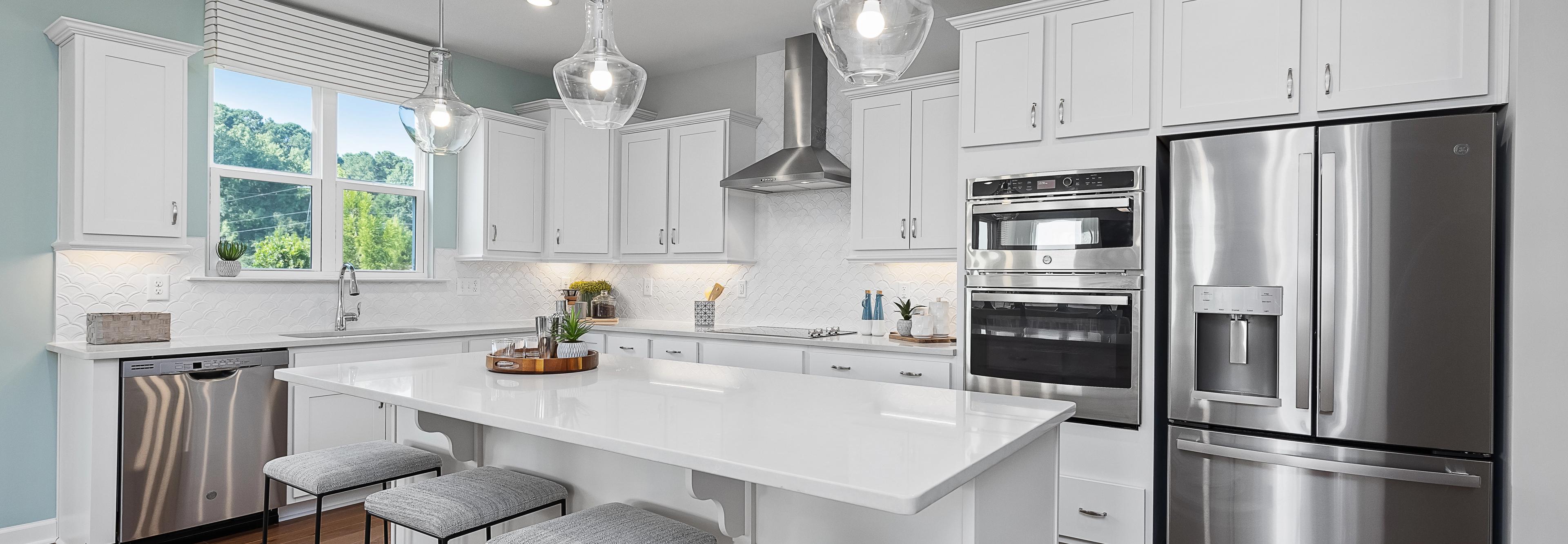 Contemporary white kitchen with island, stainless appliances, pendant lights at Enclave at Belmont, Belmont NC by Davidson Homes