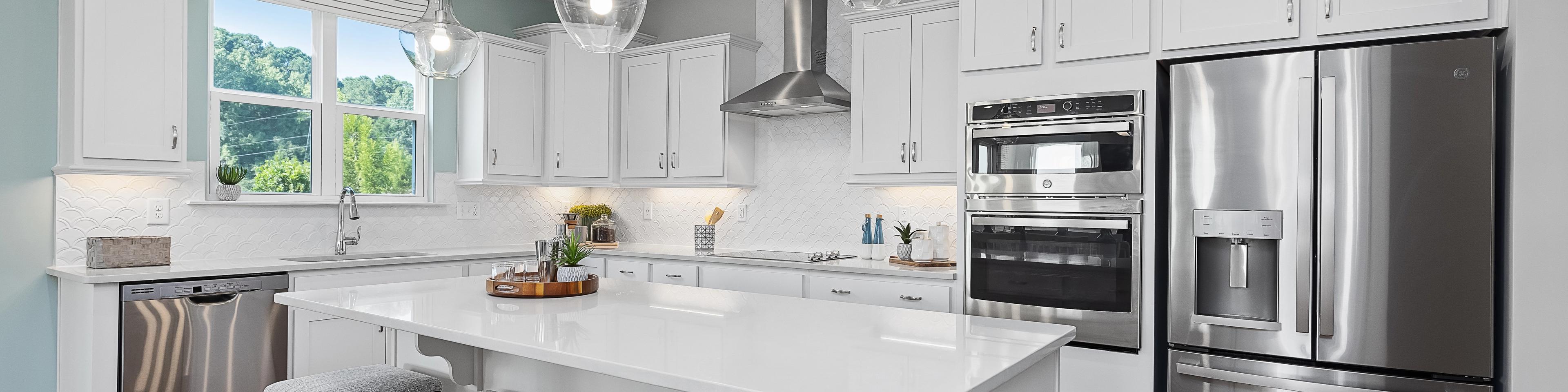 Contemporary white kitchen with island, stainless appliances, pendant lights at Enclave at Belmont, Belmont NC by Davidson Homes