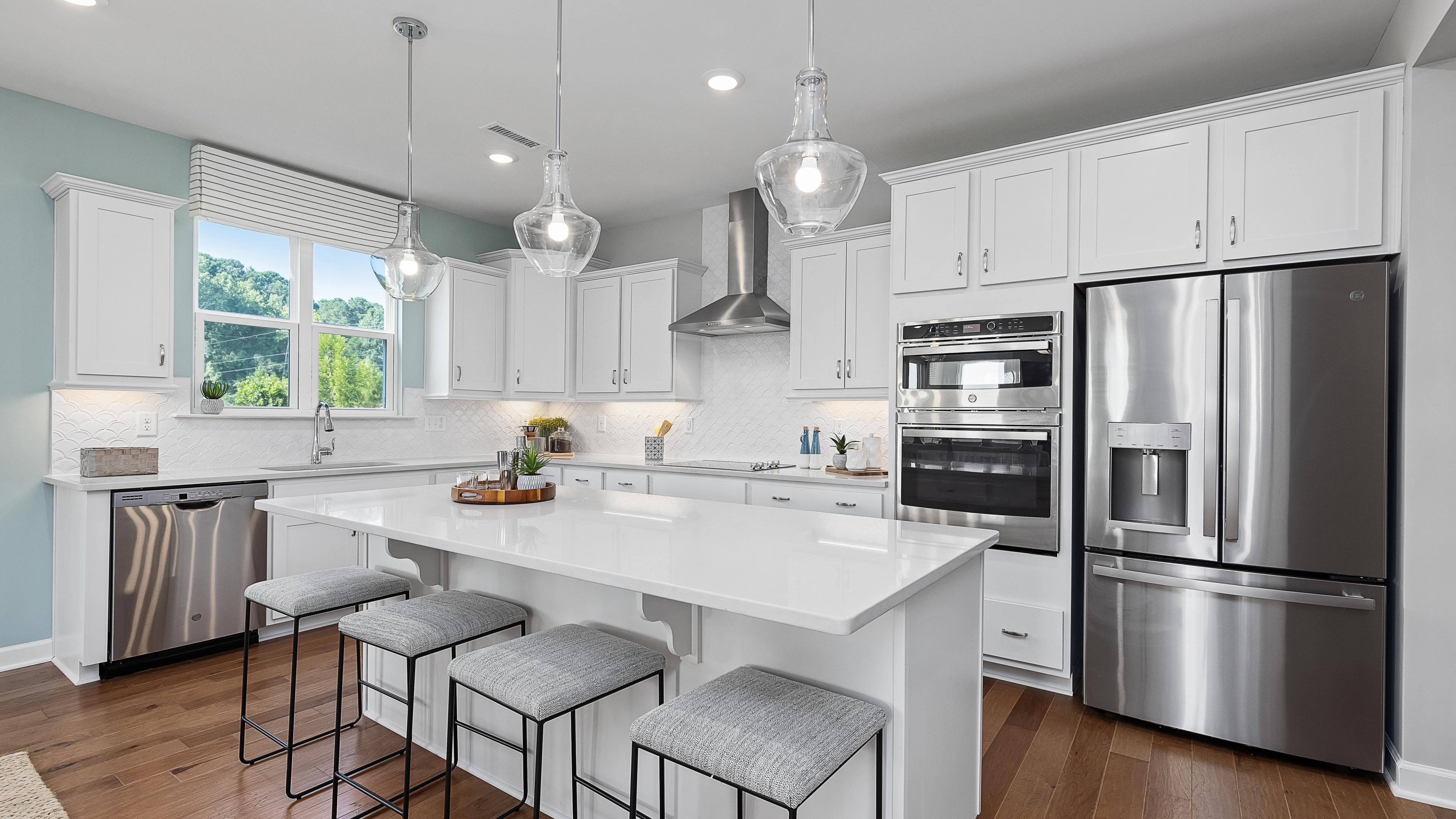 Contemporary white kitchen with island, stainless appliances, pendant lights at Enclave at Belmont, Belmont NC by Davidson Homes