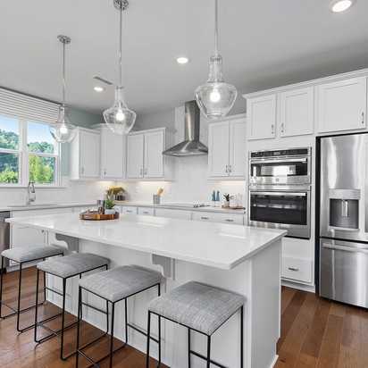 Contemporary white kitchen with island, stainless appliances, pendant lights at Enclave at Belmont, Belmont NC by Davidson Homes