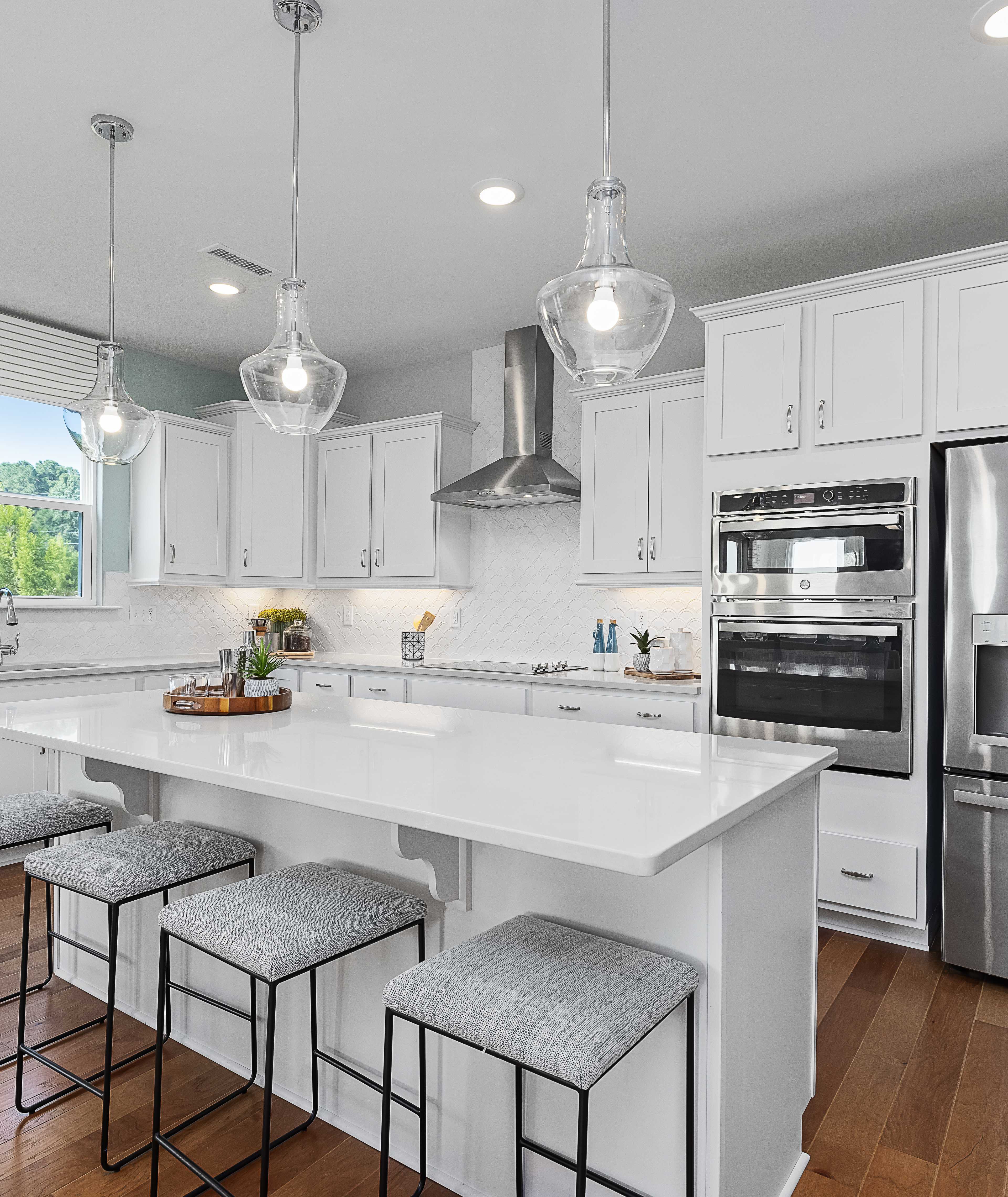 Contemporary white kitchen with island, stainless appliances, pendant lights at Enclave at Belmont, Belmont NC by Davidson Homes