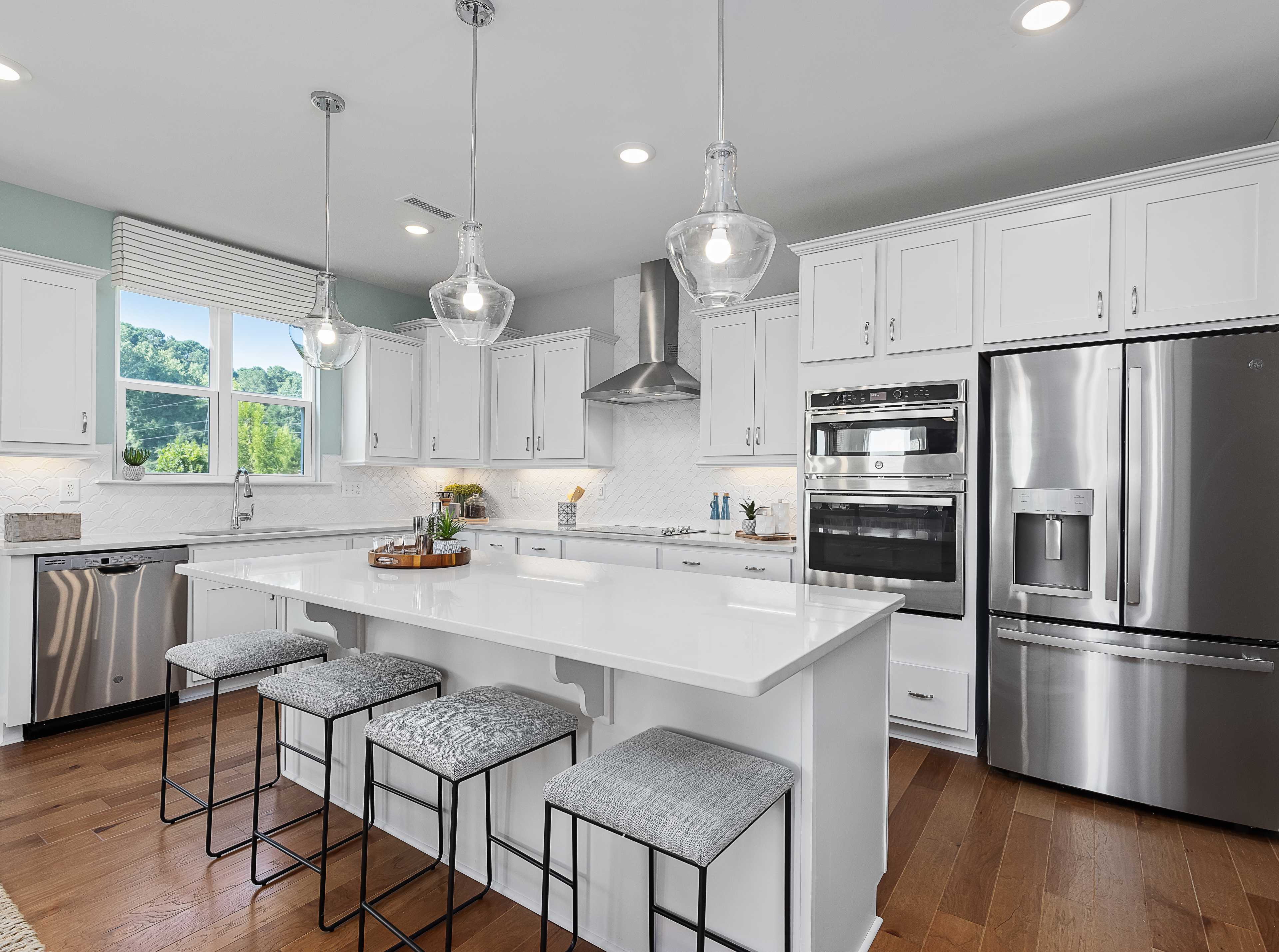 Contemporary white kitchen with island, stainless appliances, pendant lights at Enclave at Belmont, Belmont NC by Davidson Homes
