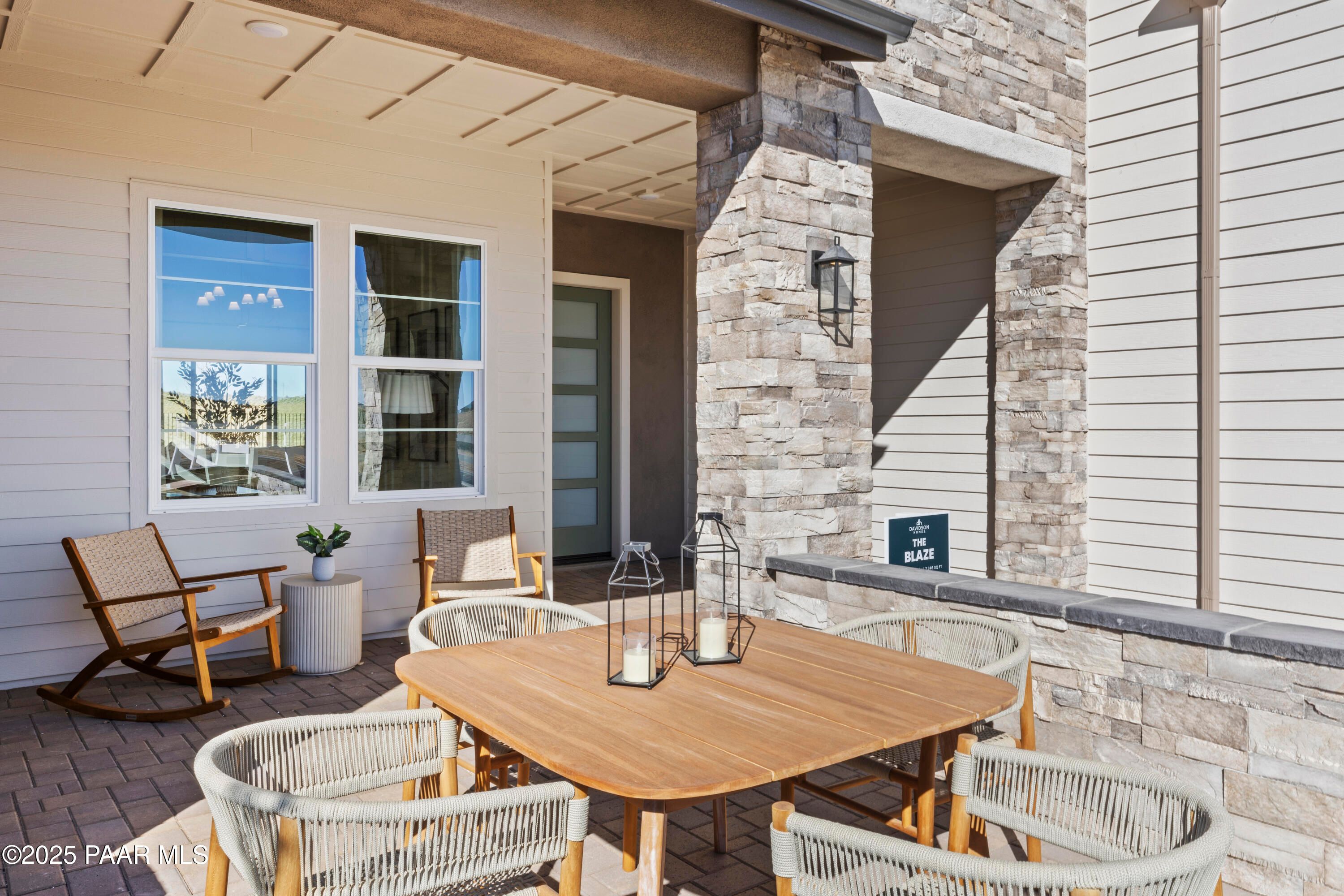 Covered patio with teak dining table, wicker chairs, and lanterns in Davidson Homes The Blaze D, Hidden Hills, Prescott, AZ